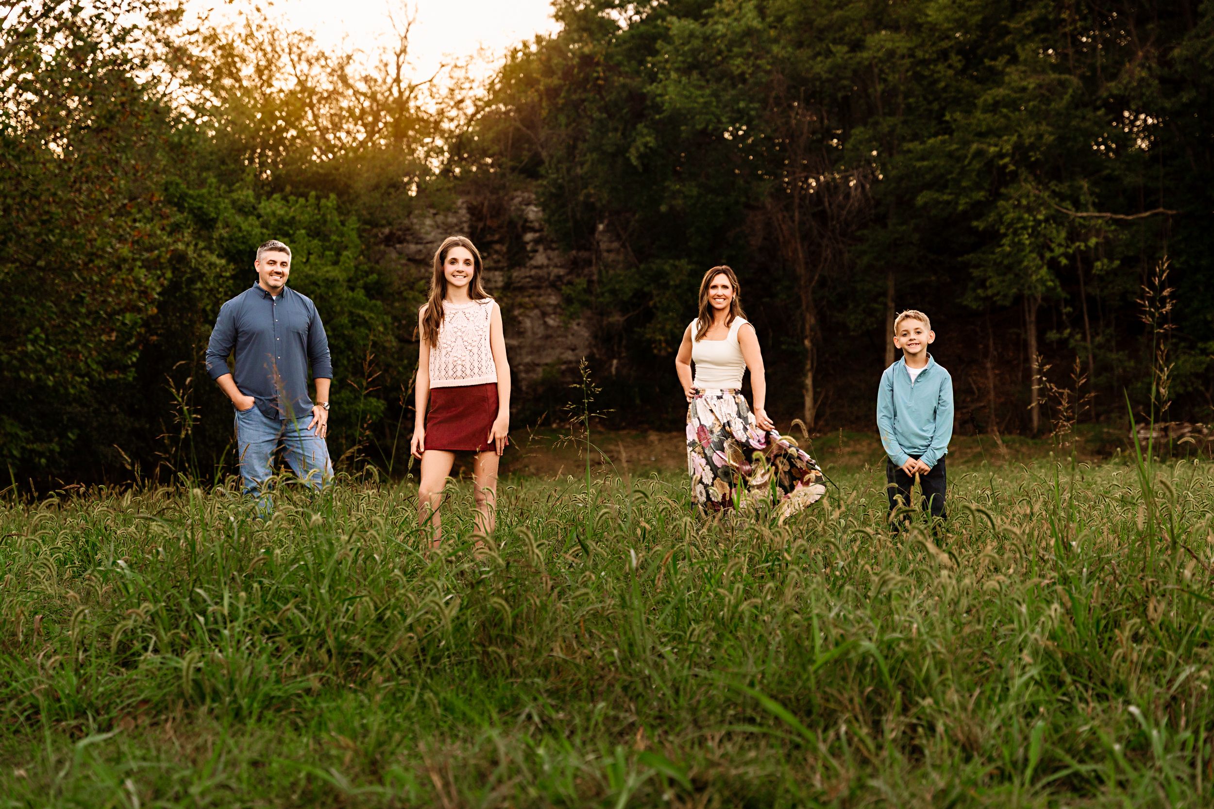 A group enjoys a casual outdoor photo session in a grassy field at golden hour.
