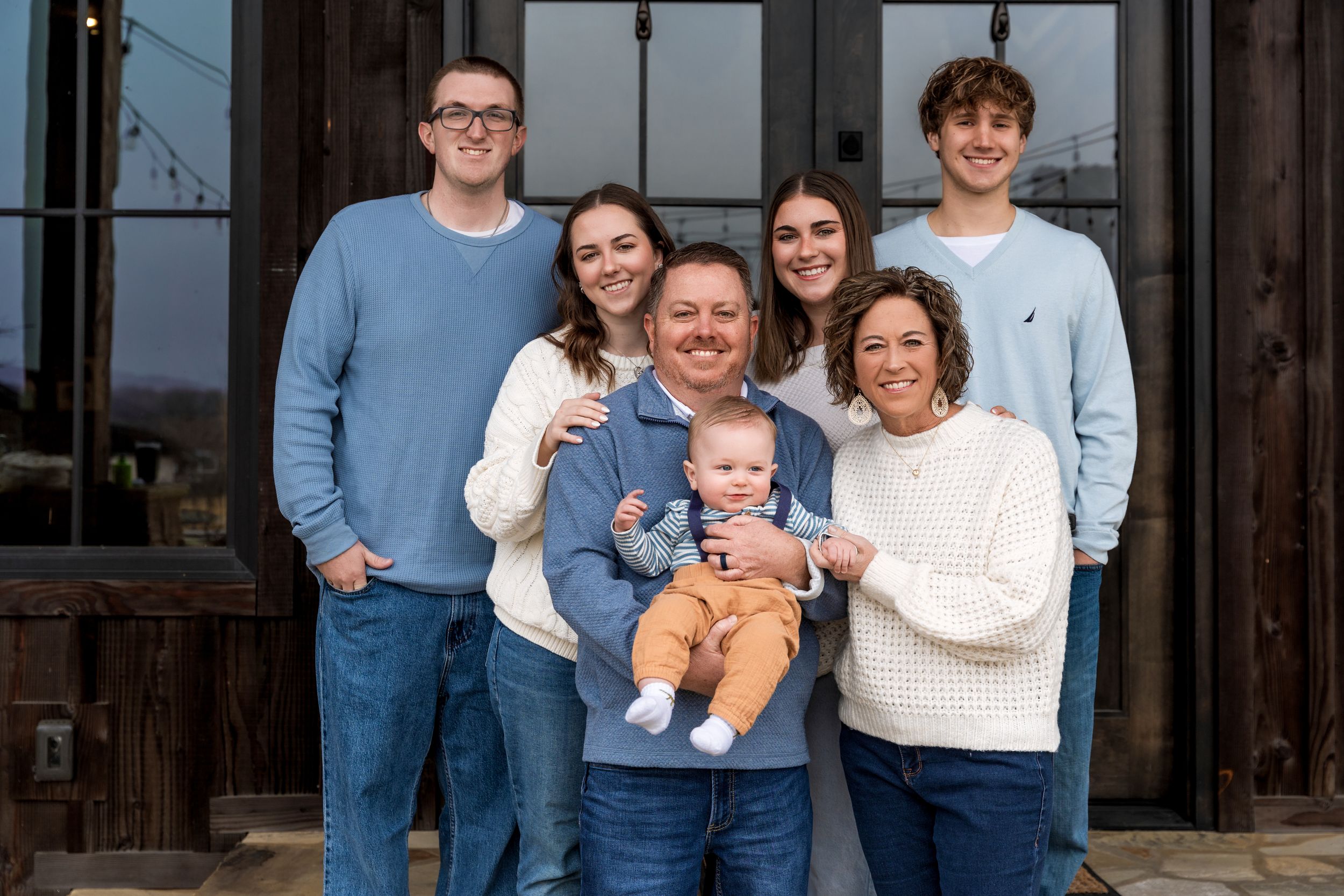 A group stands together for a casual portrait outside a rustic building on a bright day.