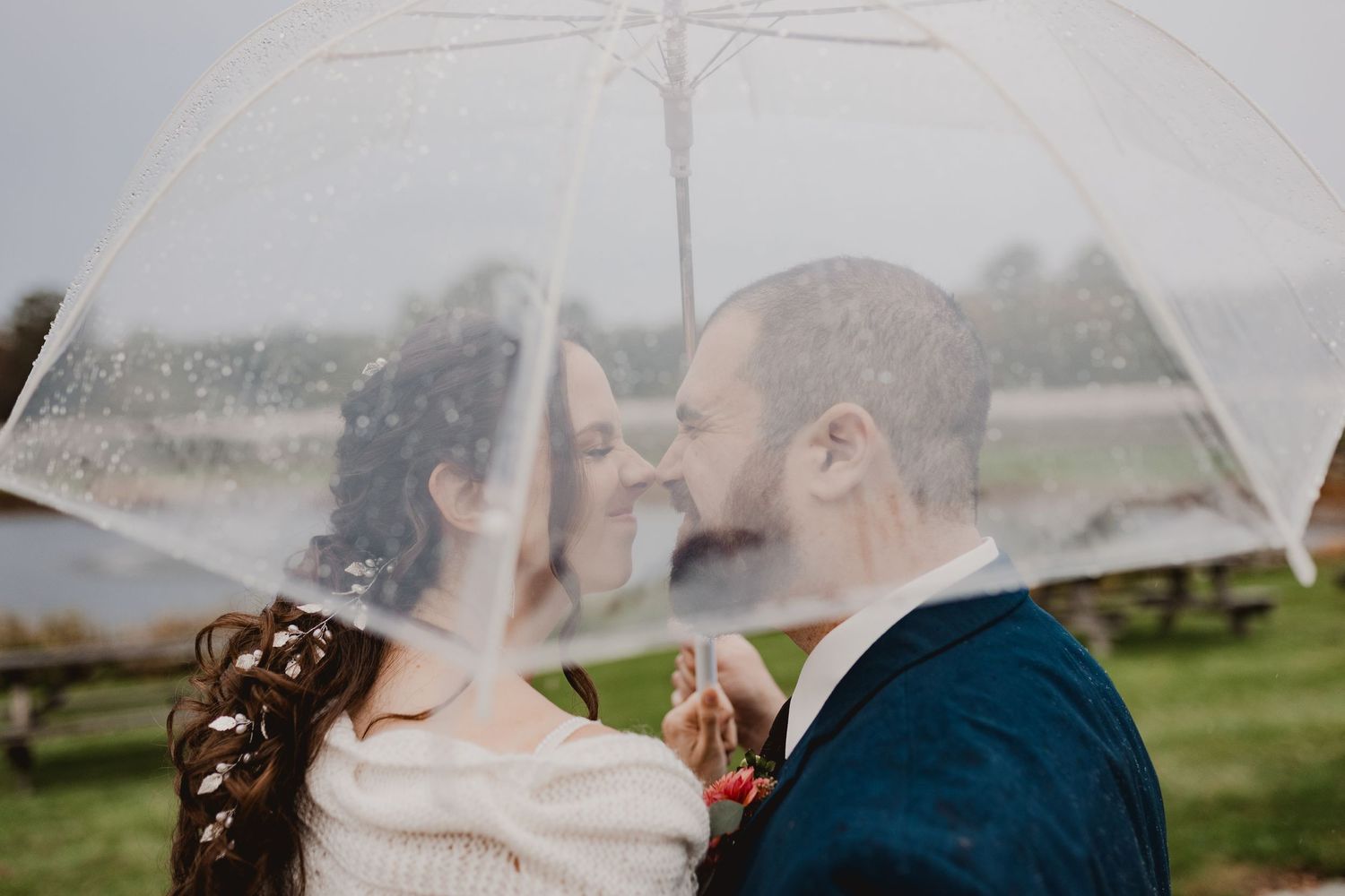A romantic moment captured under a clear umbrella during a wedding photoshoot.