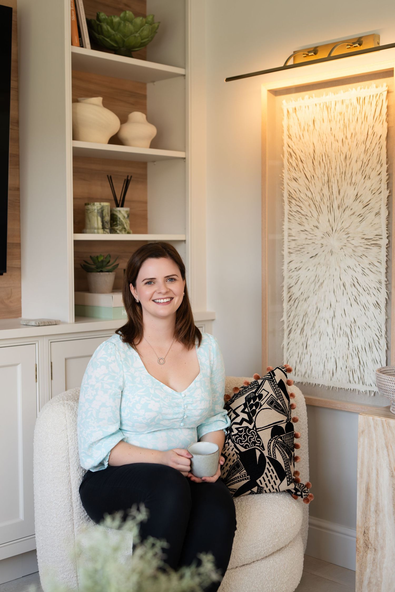 A cozy reading nook features built-in shelves, decorative artwork, and comfortable seating with a throw pillow.