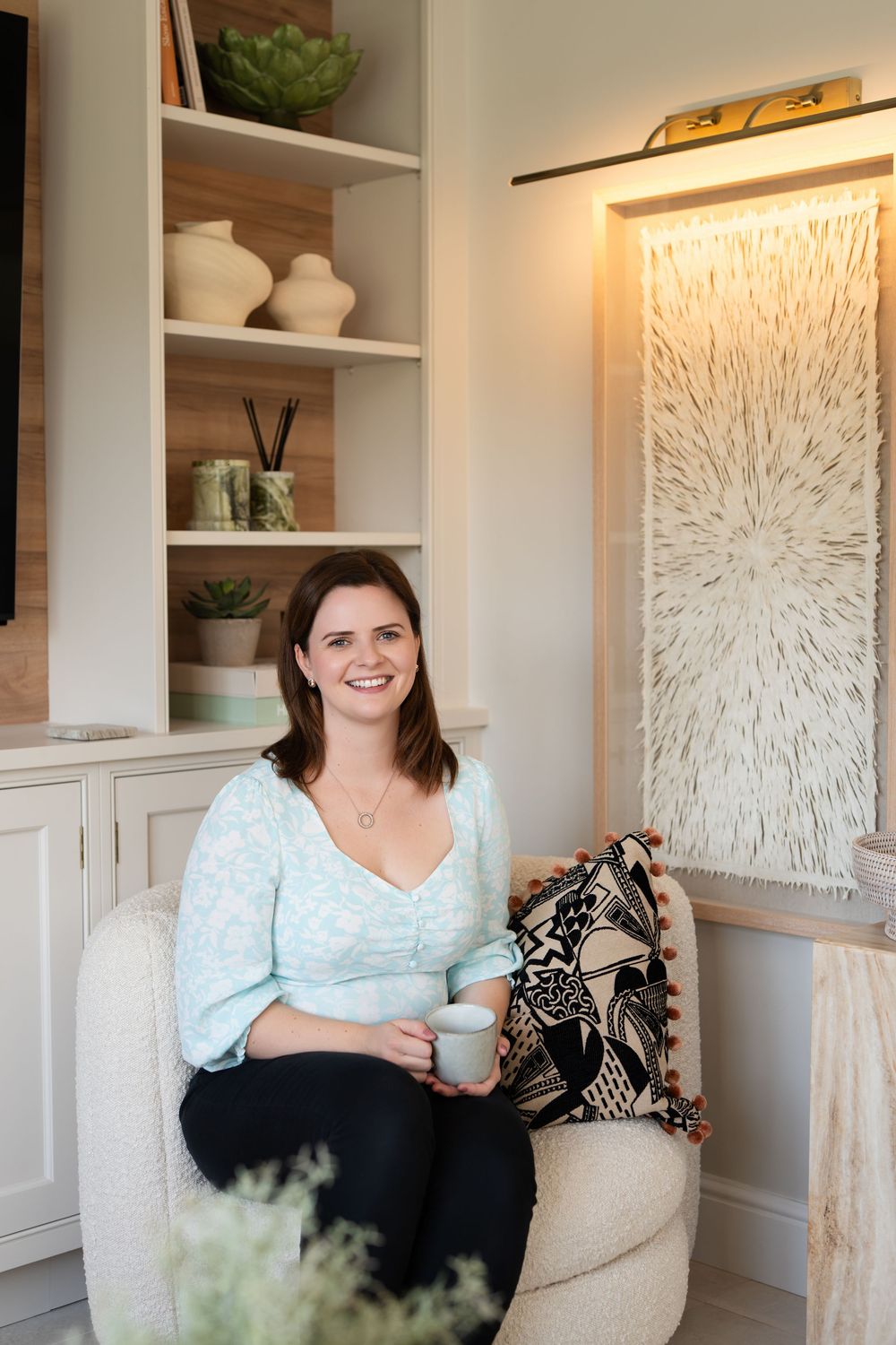 A cozy reading nook features built-in shelves, decorative artwork, and comfortable seating with a throw pillow.