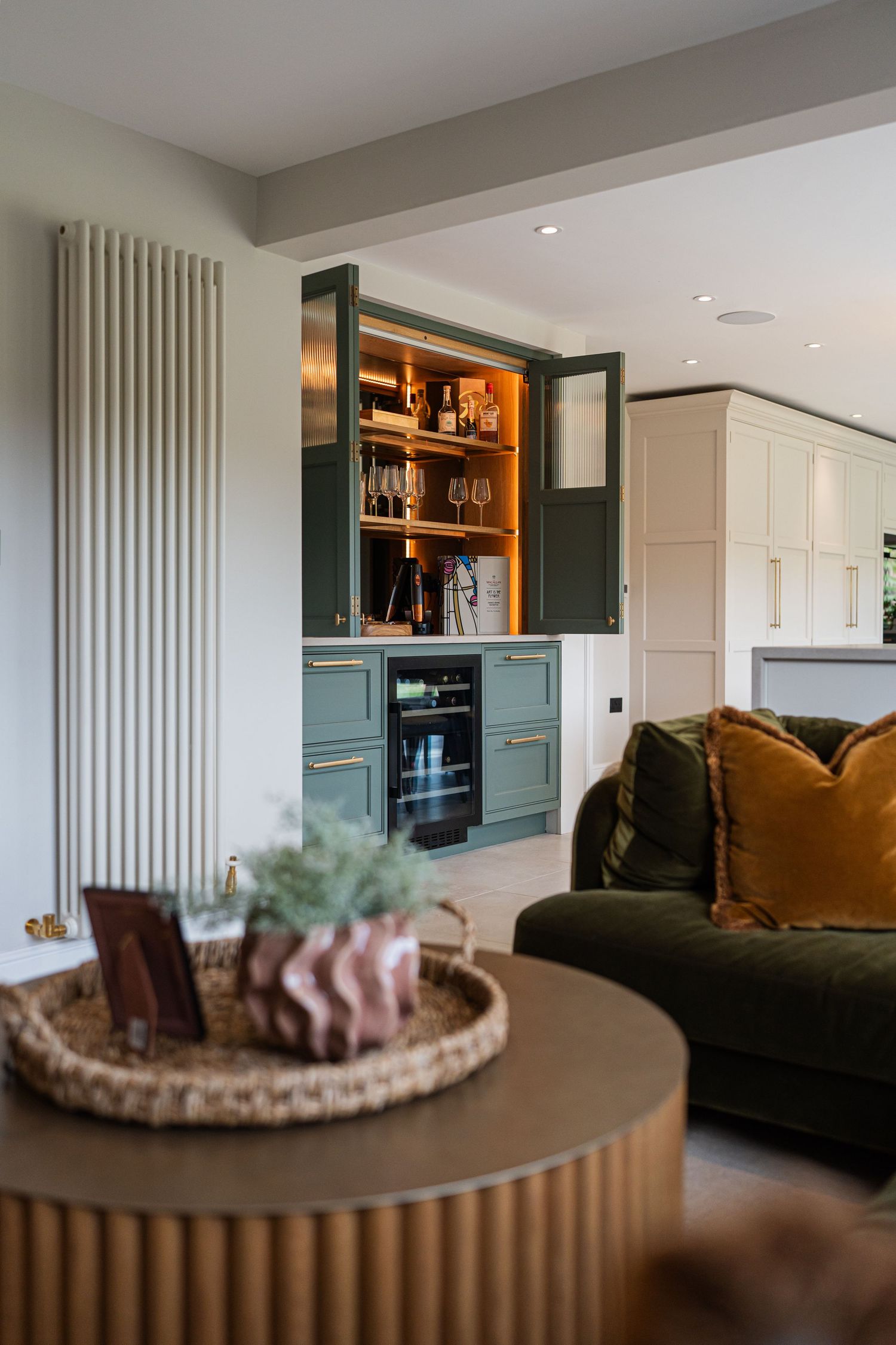 Modern living room with teal built-in cabinets, a velvet sofa, and a round wooden coffee table with decorative tray.