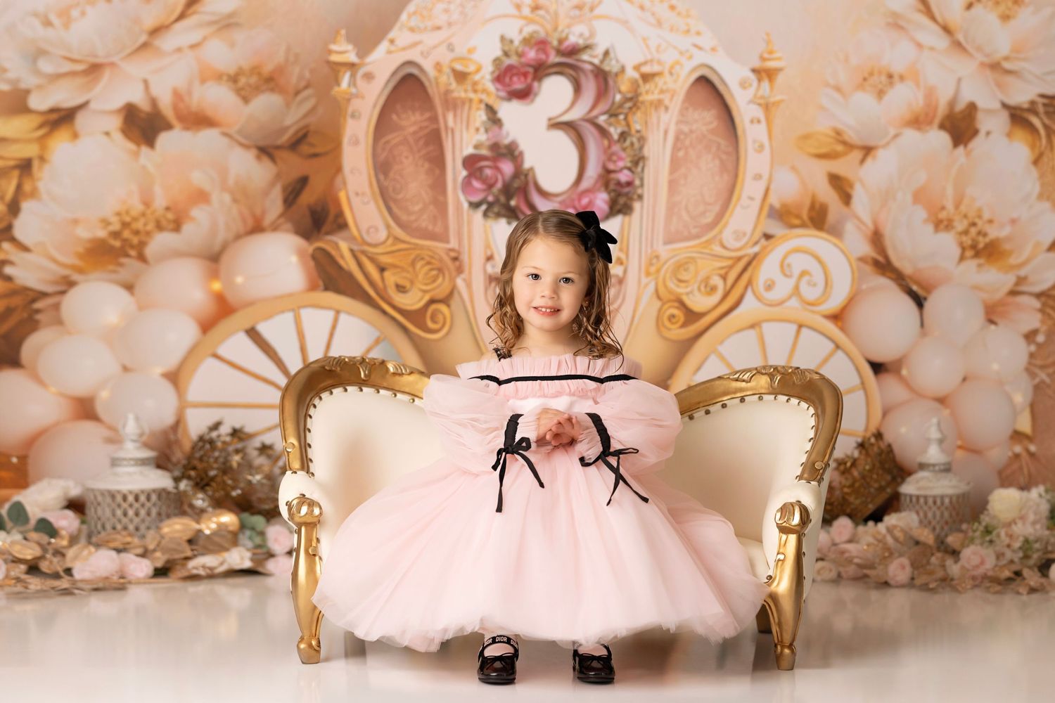 Elegant gold carriage chair with pink floral backdrop and decorative number 3 ornament for birthday celebration.
