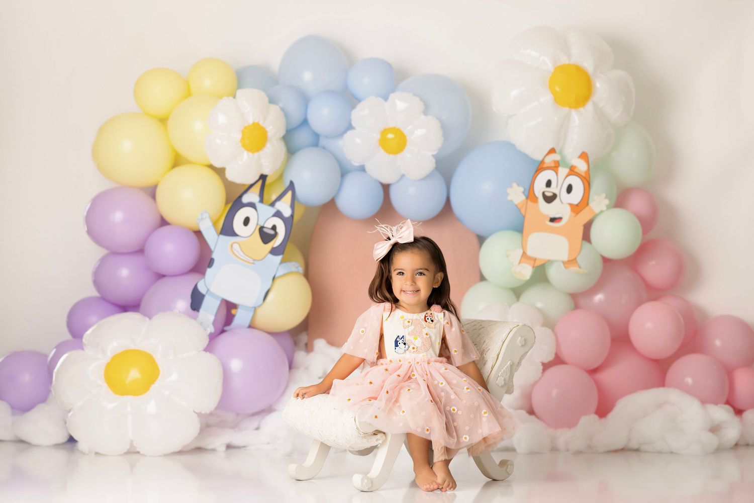 Sweet pastel balloon backdrop with white daisies and playful teddy bear designs creates a dreamy photo setting.