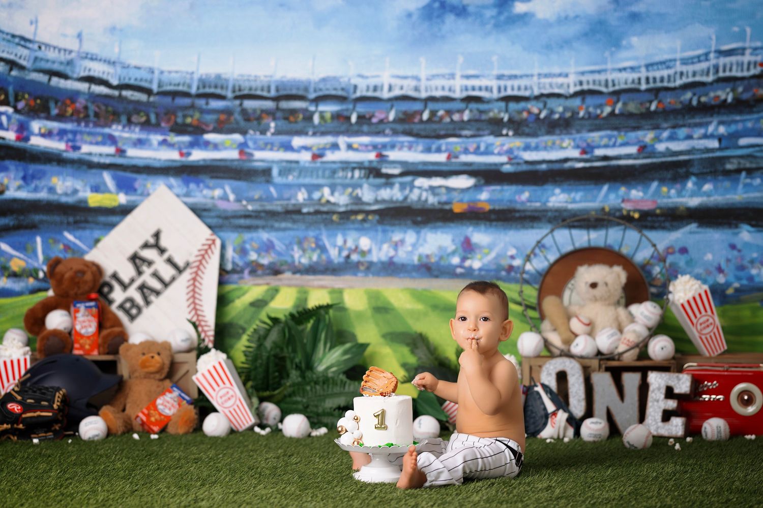 First birthday sports theme photo setup with baseball decorations and stadium backdrop.