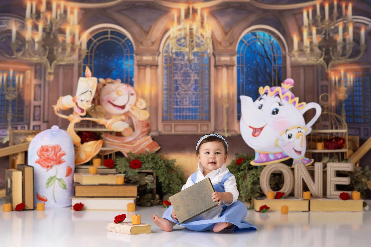 A themed Beauty and the Beast birthday setup with large decorative teapot and book props in an elegant ballroom setting.