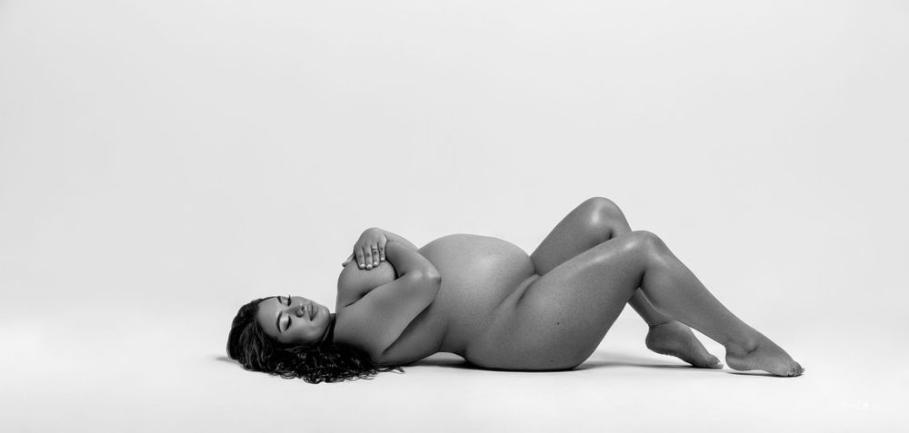 Elegant black-and-white maternity portrait of an expecting mother lying down, embracing the beauty of motherhood.