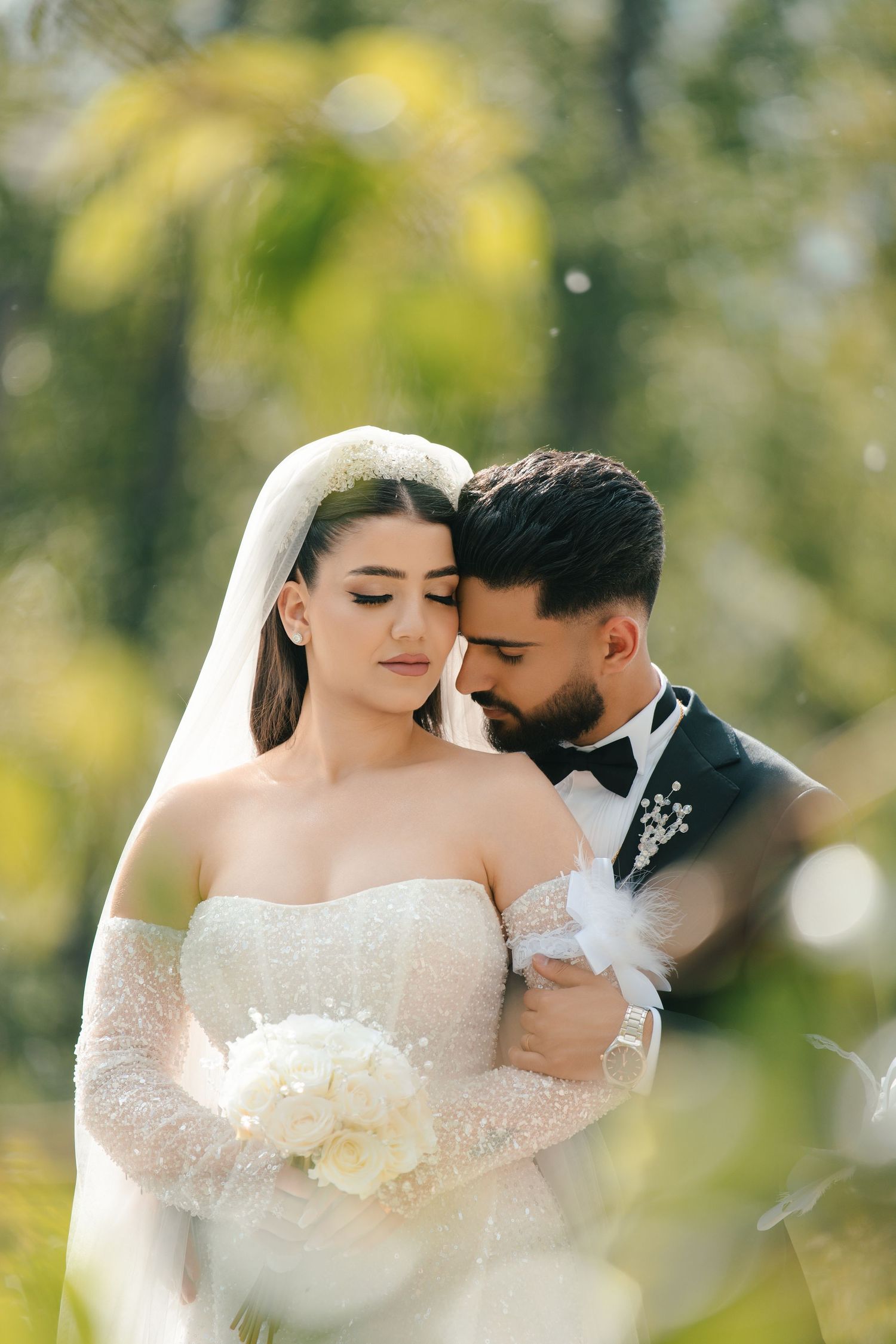 Intimate wedding portrait with bride holding white bouquet against soft bokeh background.
