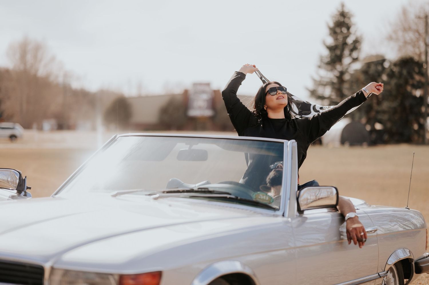 A joyful moment in a vintage silver convertible car on a winter day.
