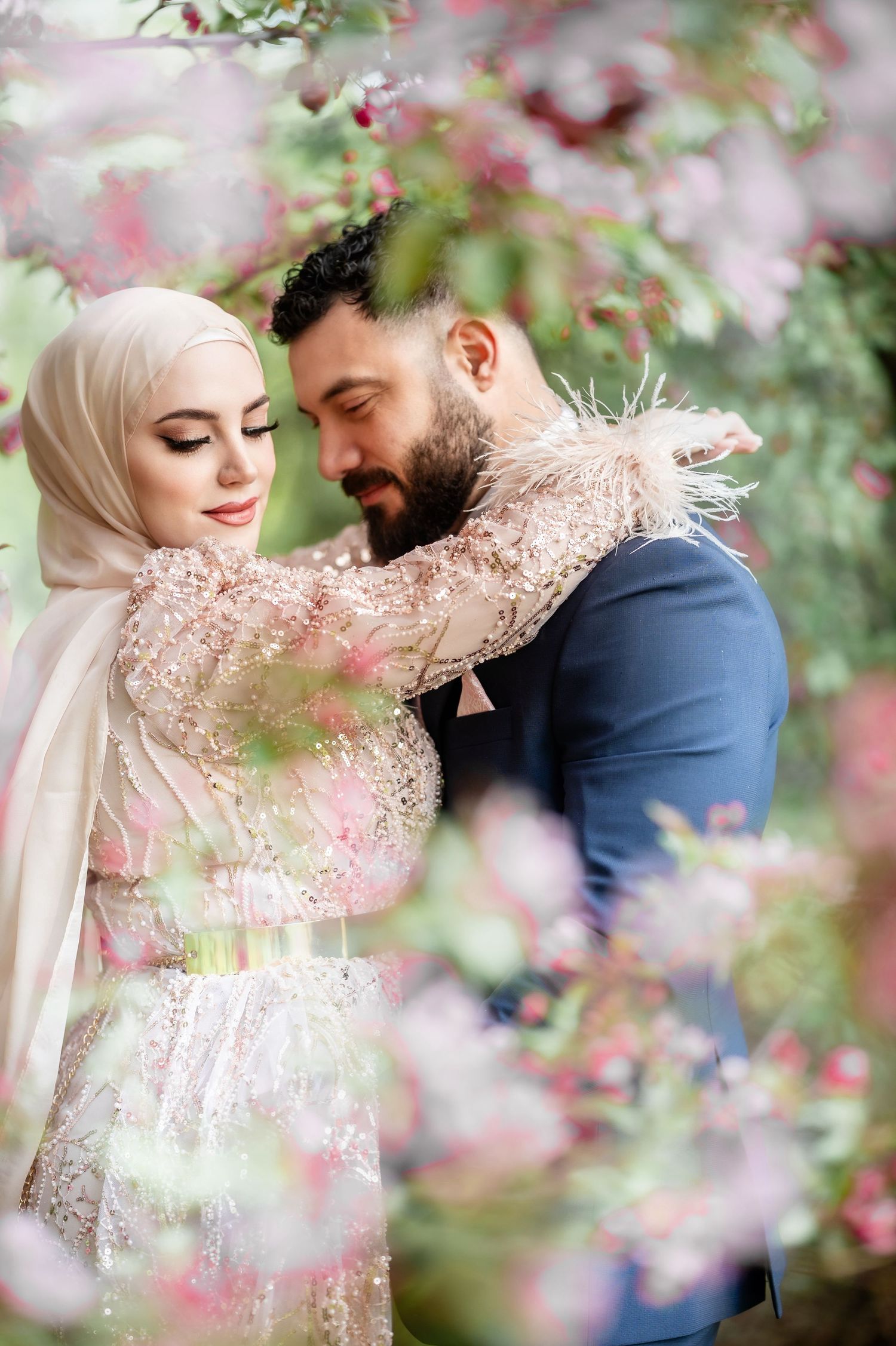 A romantic springtime portrait with pink blossoms framing the couple.