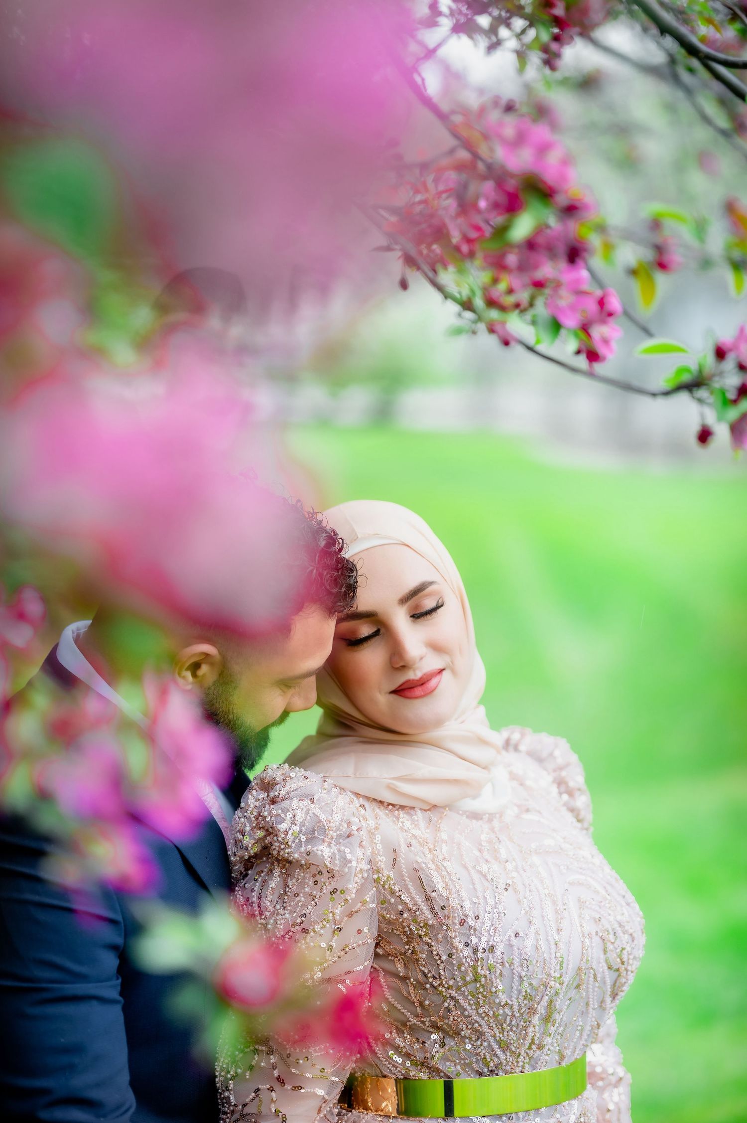 A tender moment captured among blooming pink flowers in a garden setting.