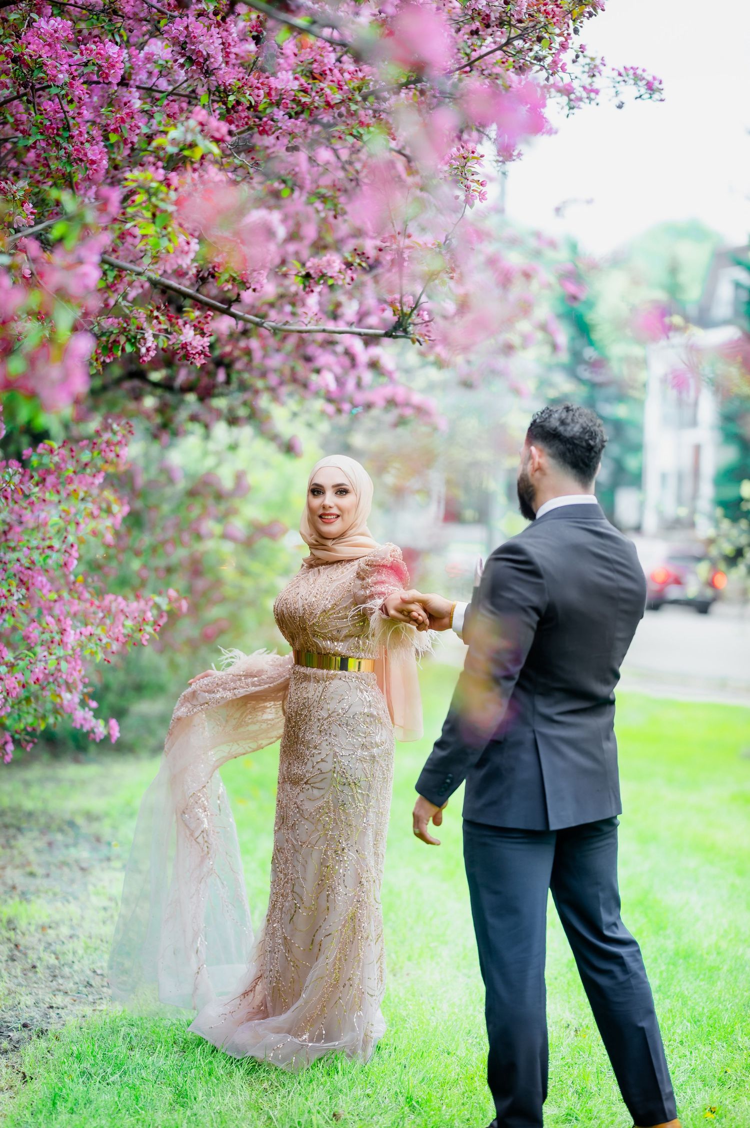 A romantic moment under blooming cherry trees with flowing formal attire.