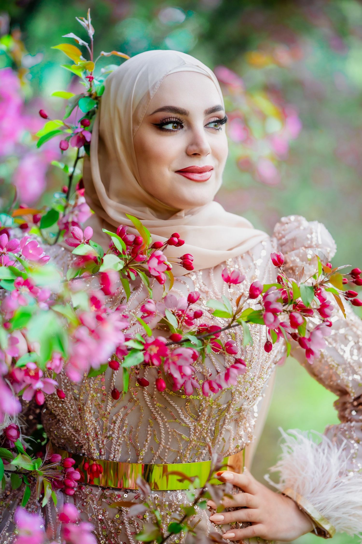 A portrait among pink spring blossoms wearing an elegant beaded dress.