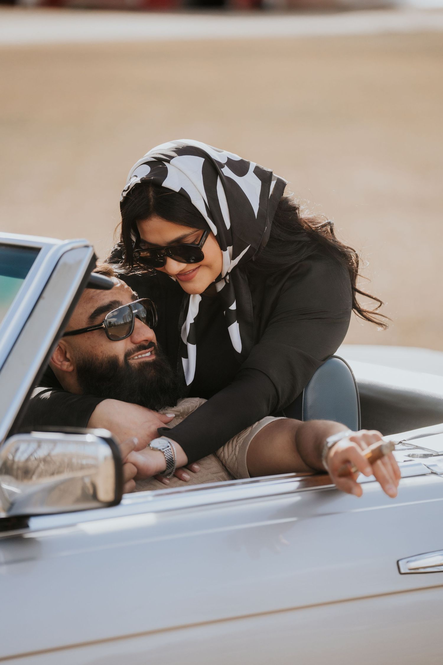 Romantic couple sharing an intimate moment in a convertible car on a sunny day.