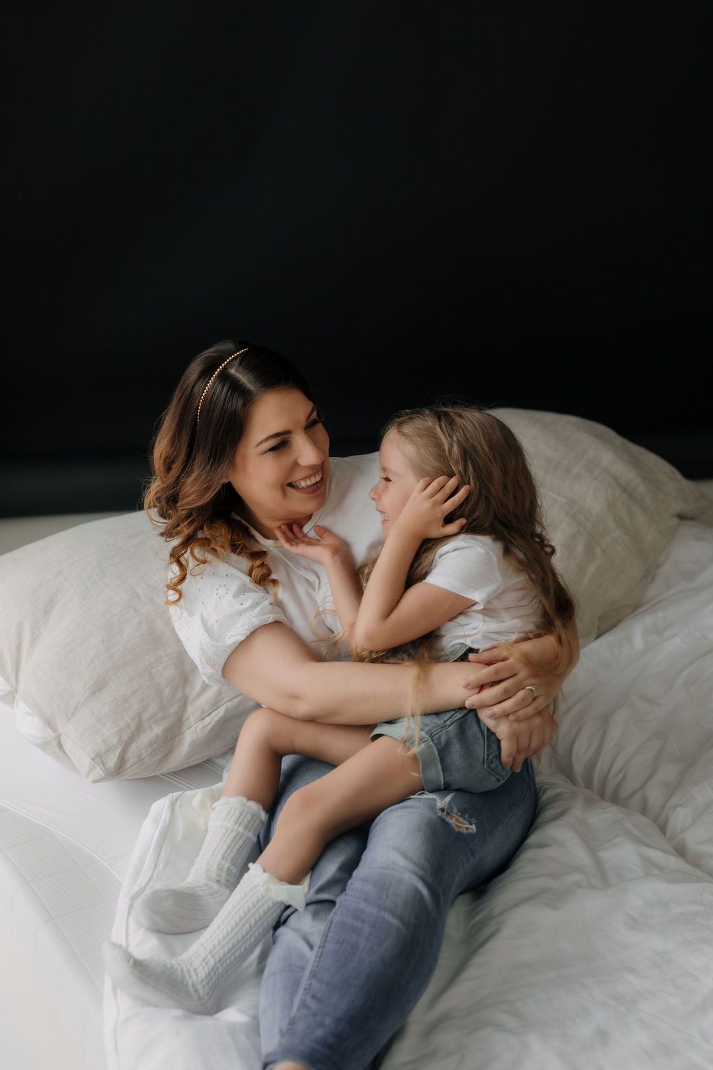 A heartwarming candid moment showing affection and laughter on white bedding.