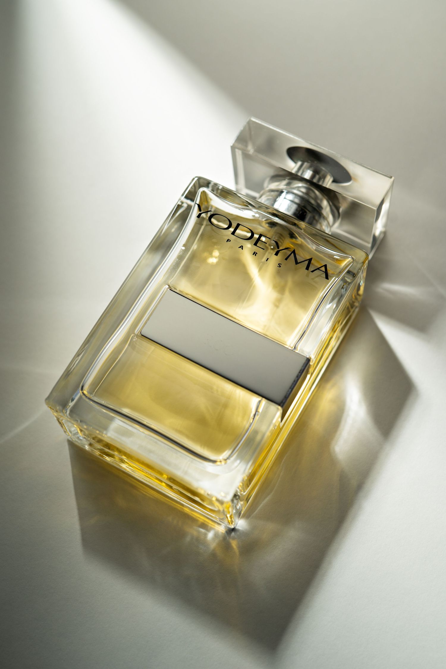 A series of artistic photographs showing a luxury perfume bottle from different angles in soft natural lighting.