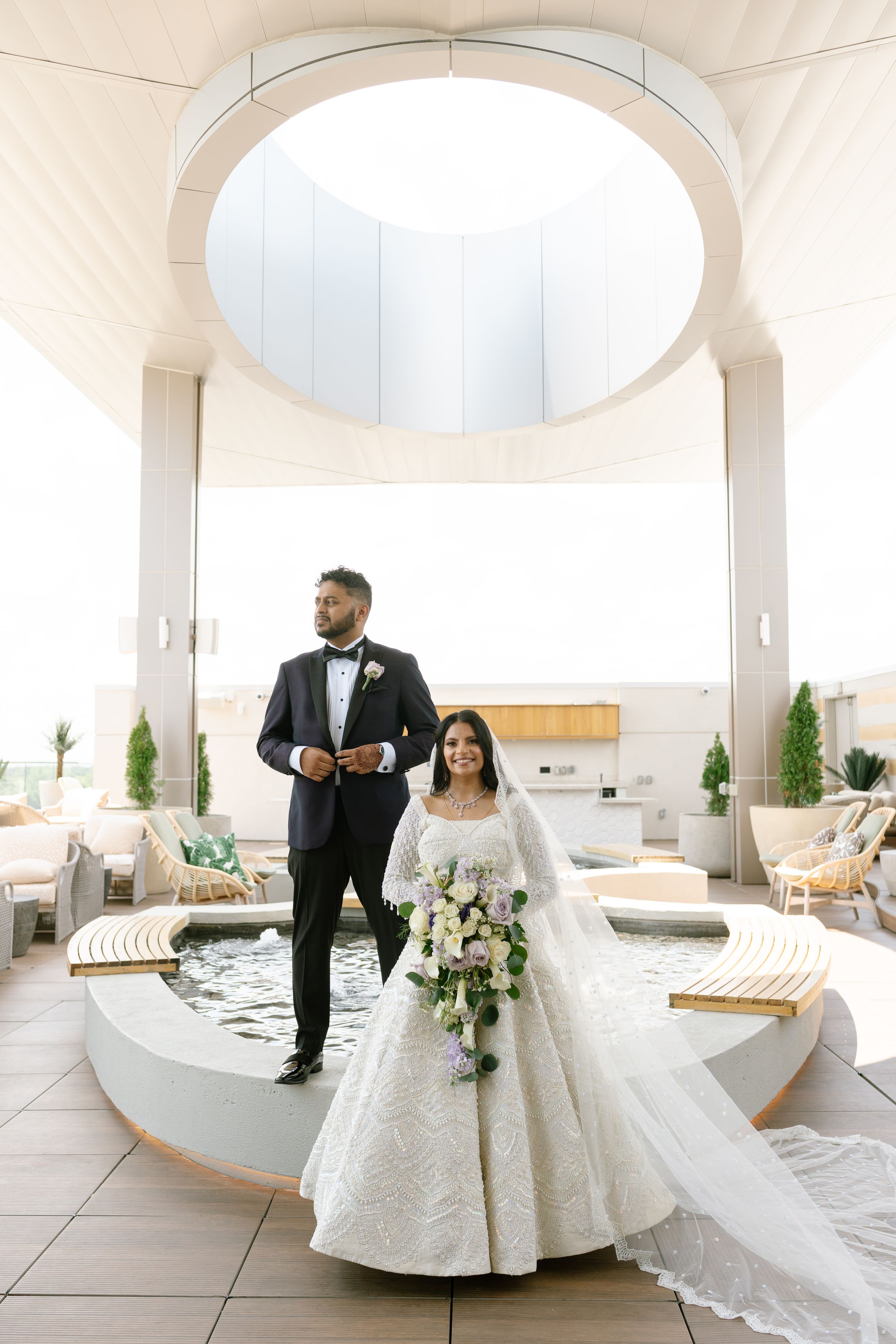 A wedding couple stands in an elegant white venue with arched ceilings and minimalist decor. Syro Malabar and Hindu Wedding.