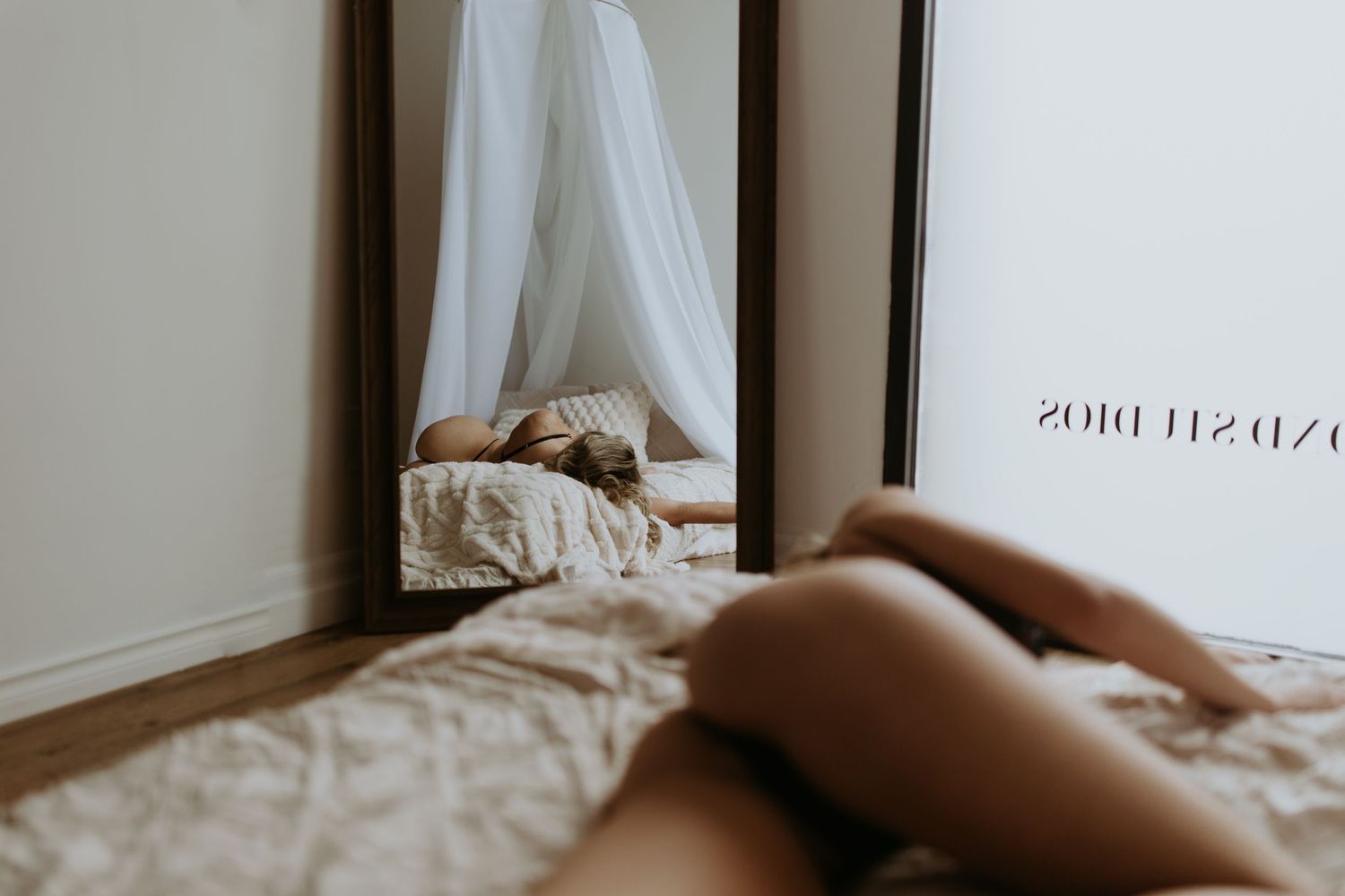 a reflection in the mirror of a woman laying on a bed