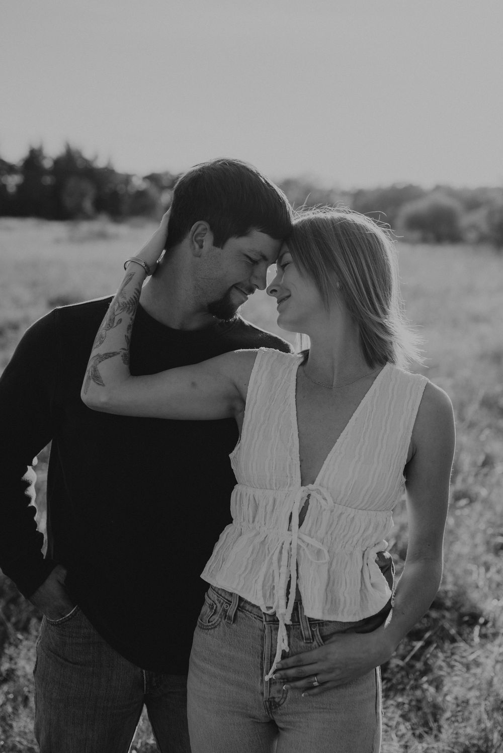 A romantic black and white photo series of a couple embracing in a meadow.
