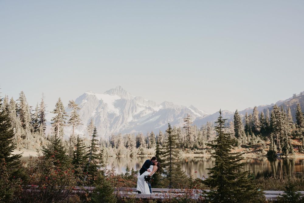 A scenic winter wedding ceremony set against snow-capped mountains and evergreen trees in a natural outdoor setting.