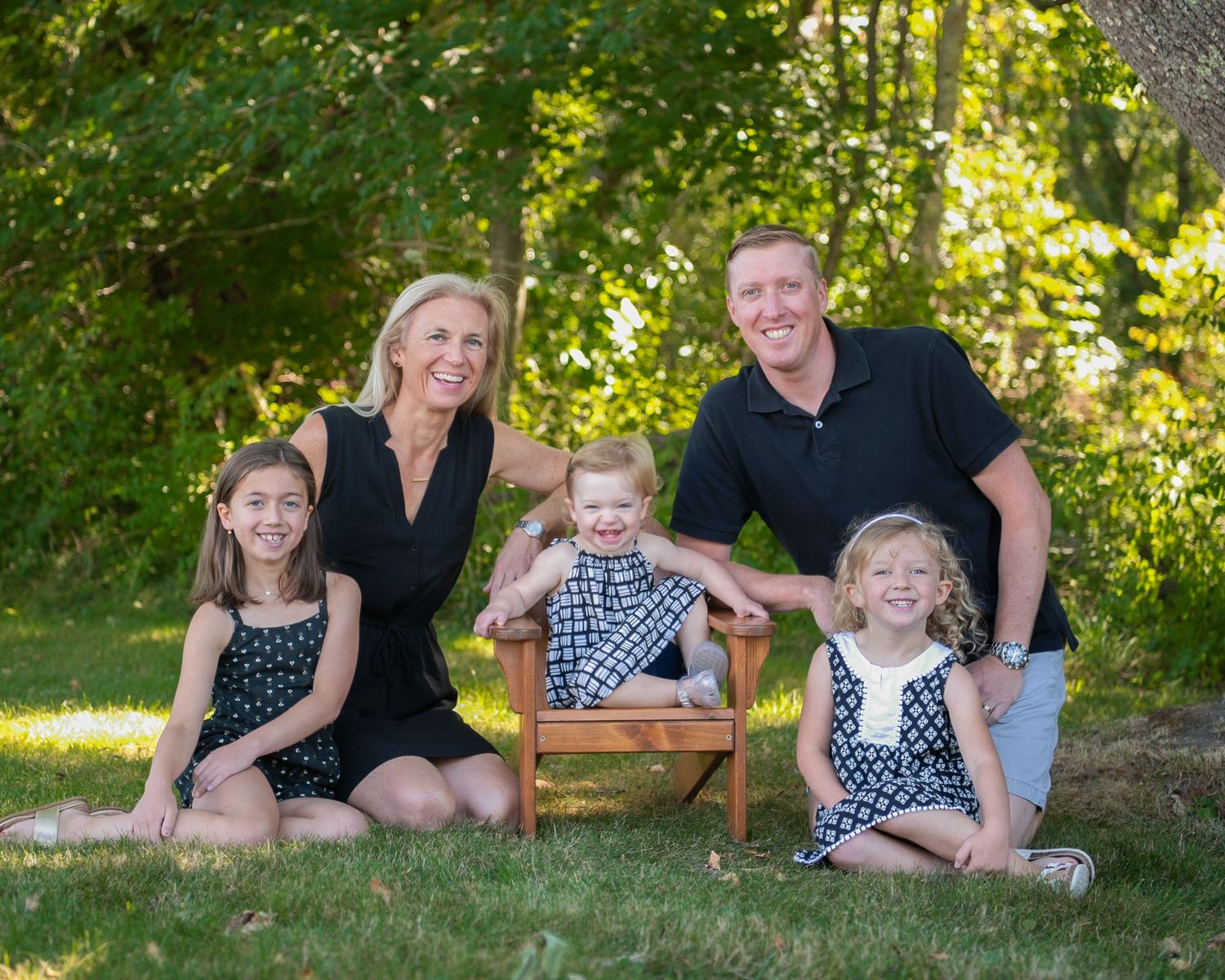 Happy family of six posing on stone steps in front of a classic door, dressed in elegant attire.