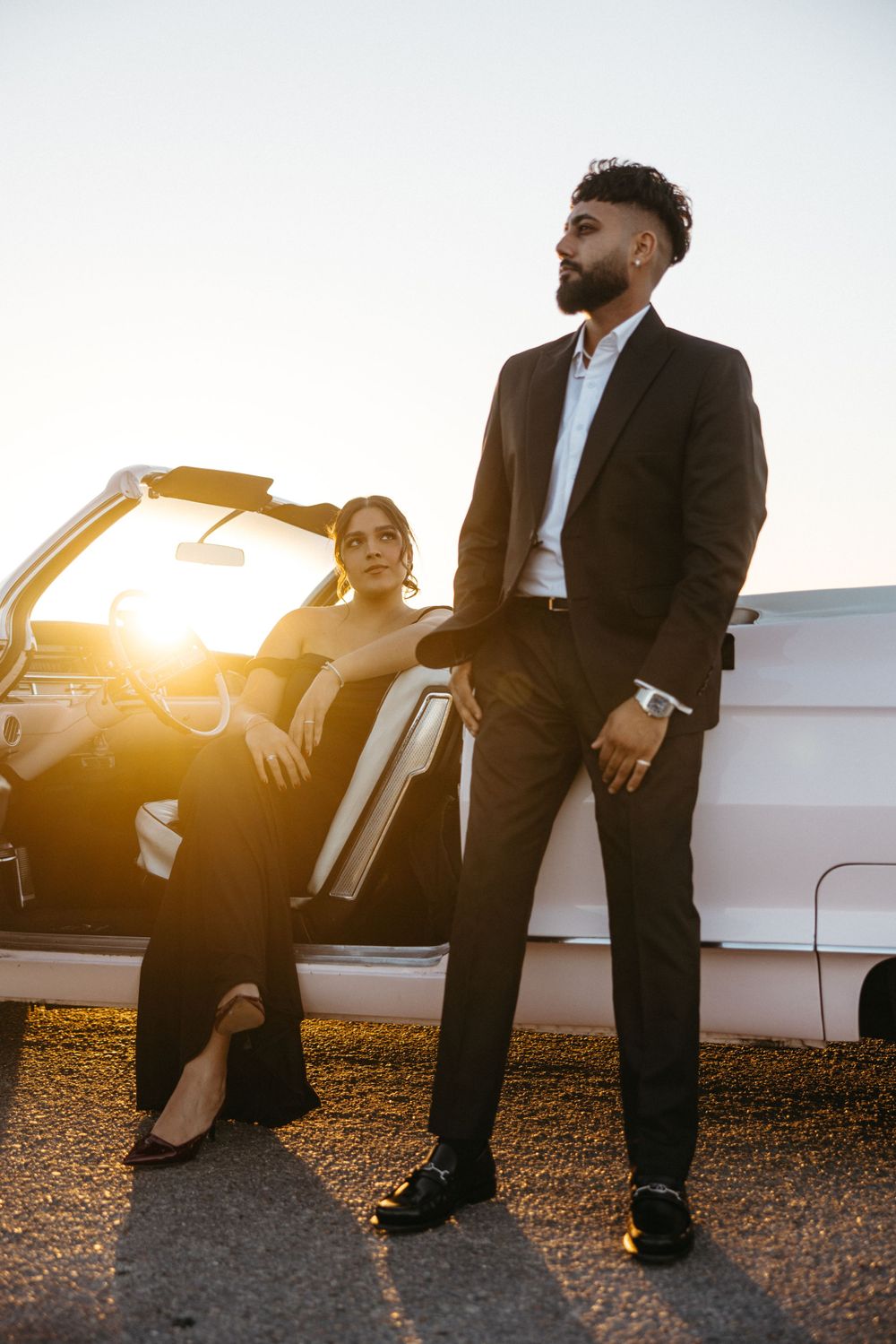 Business professionals leaning against car during golden hour sunset.