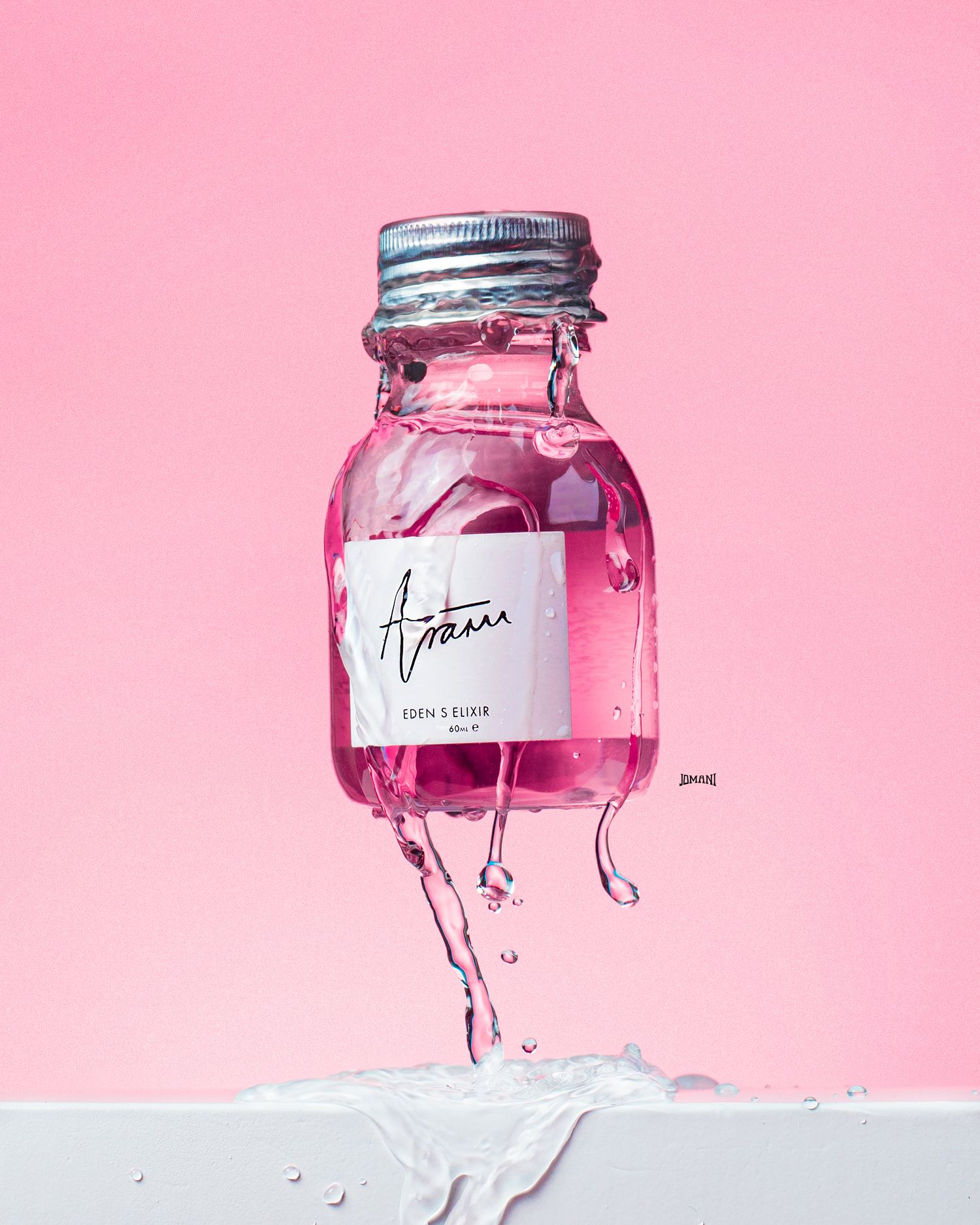 Pink glass bottle of Aram Eden's Elixir with water splashing against a pink background.
