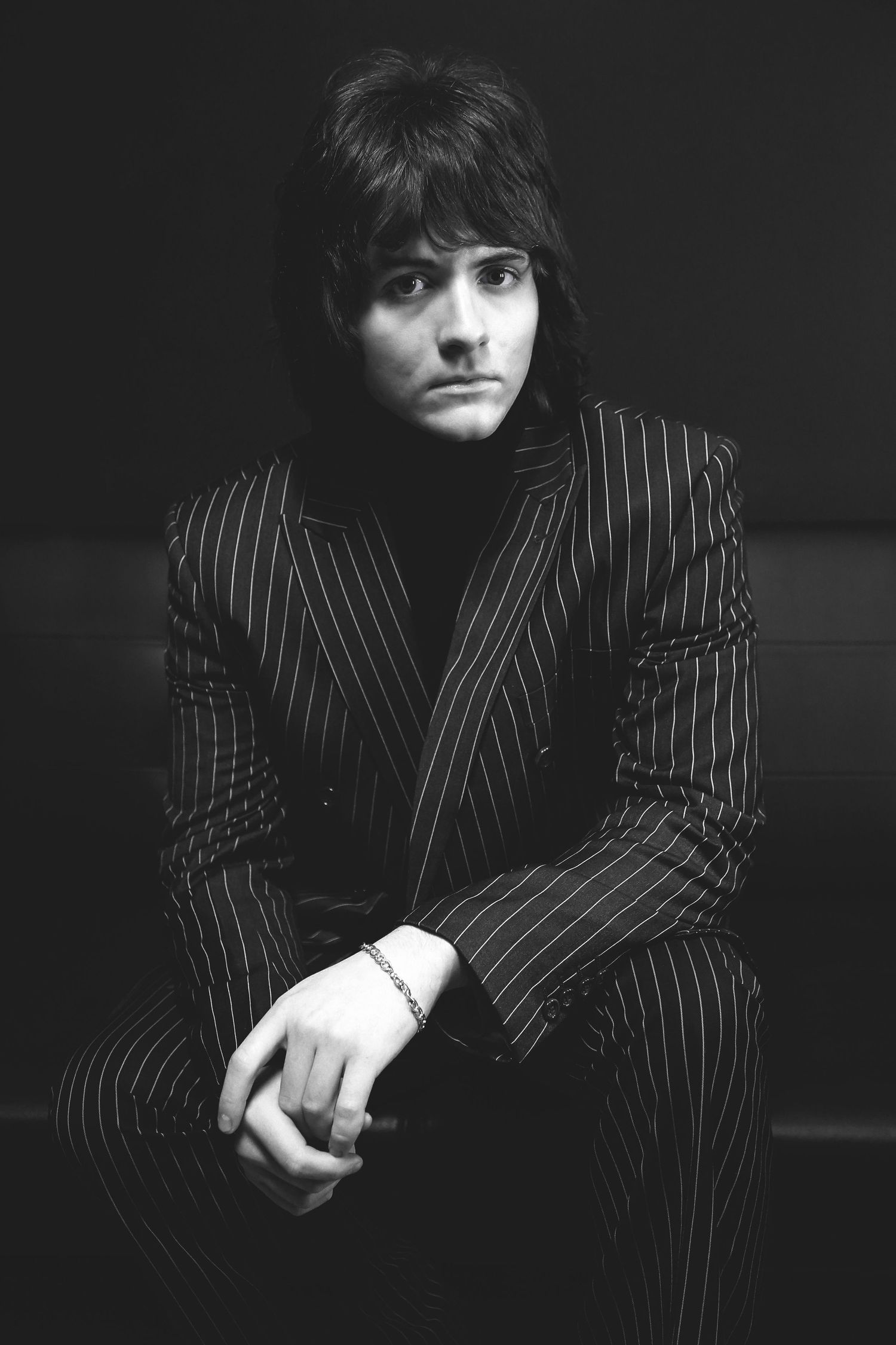 Vintage portrait in pinstripe suit against dark background.