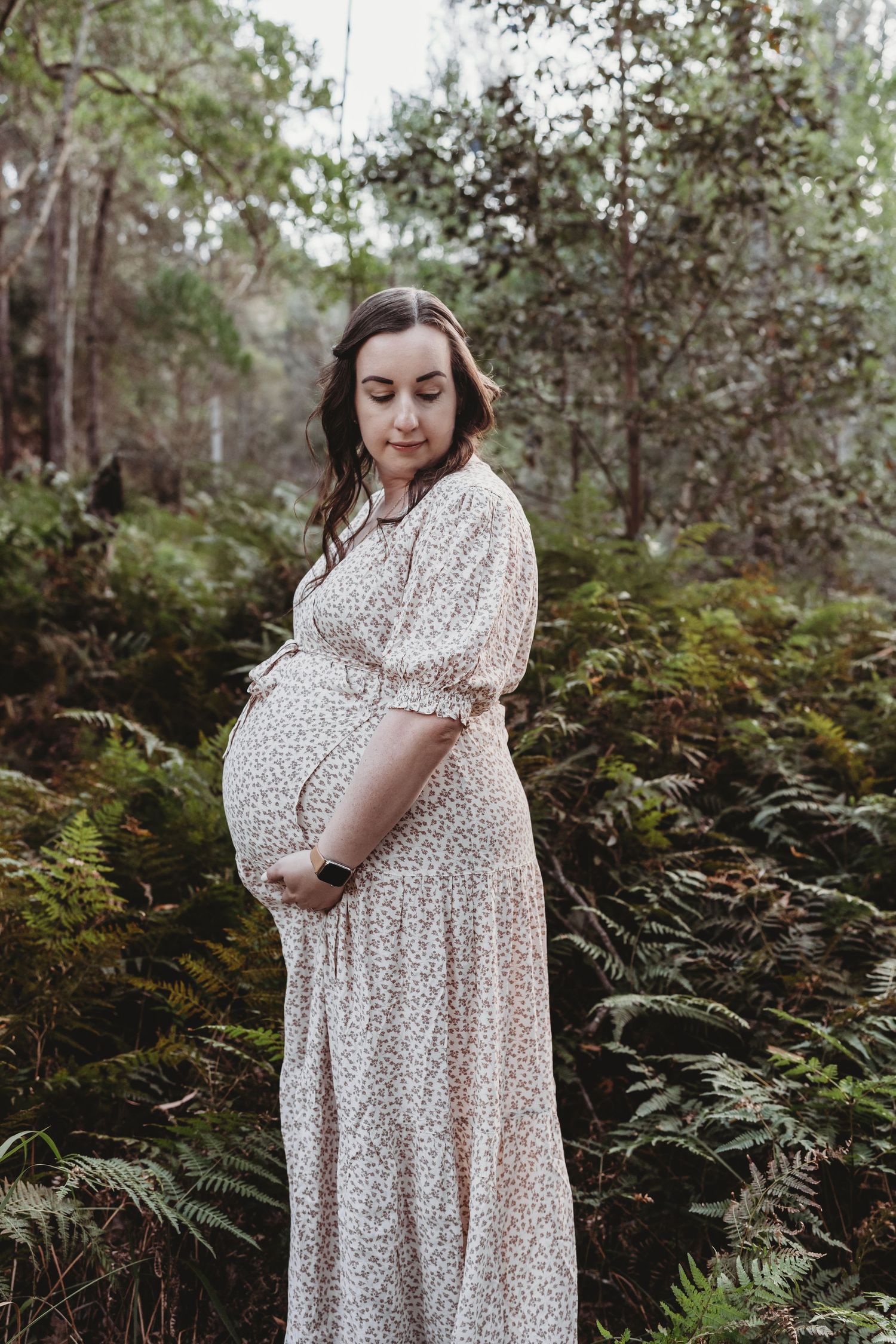 Pregnant mum to be standing in forest holding baby bump during Sydney maternity photoshoot