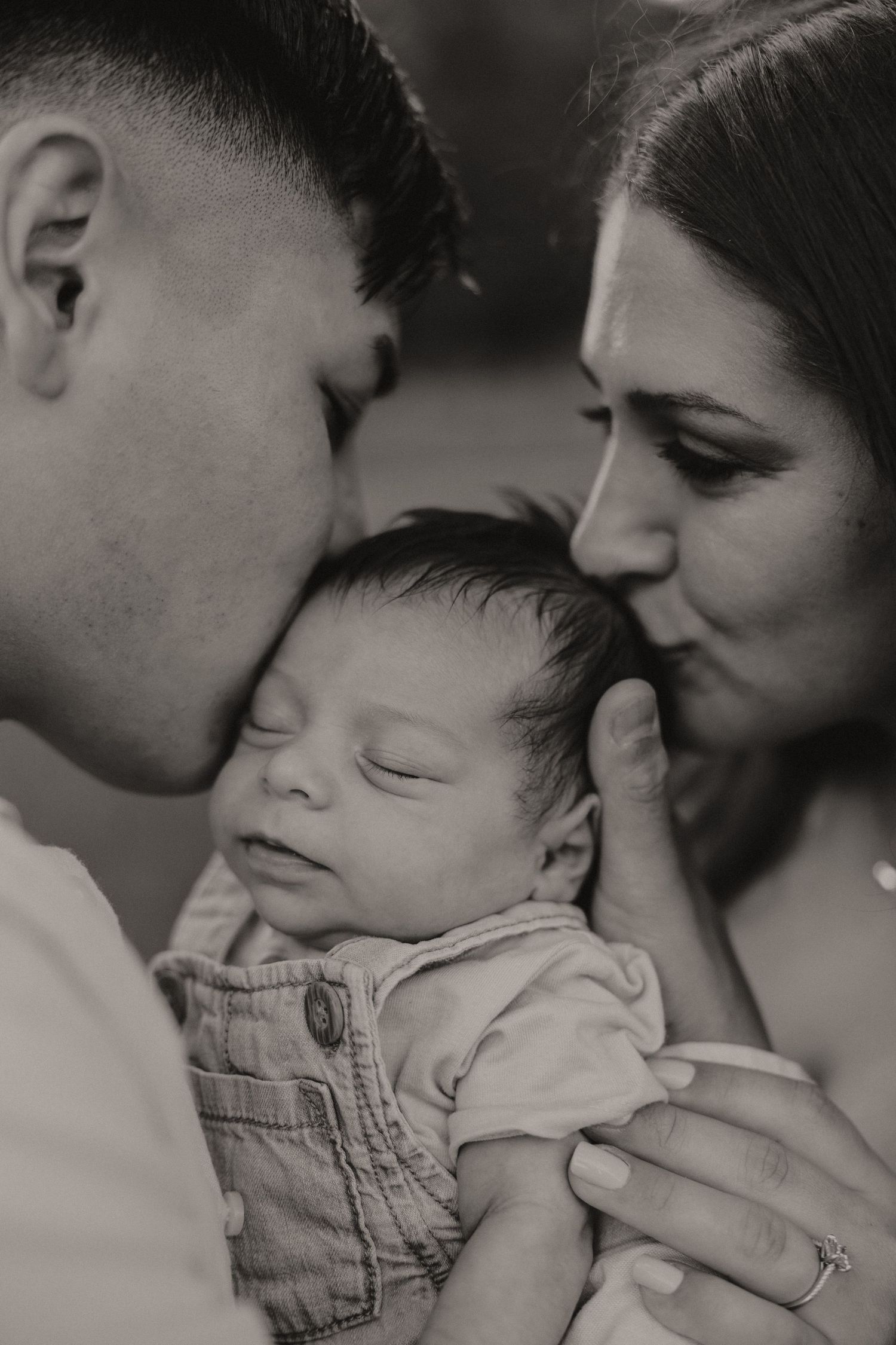 Intimate black and white portrait series showing tender moments between a baby and parents.