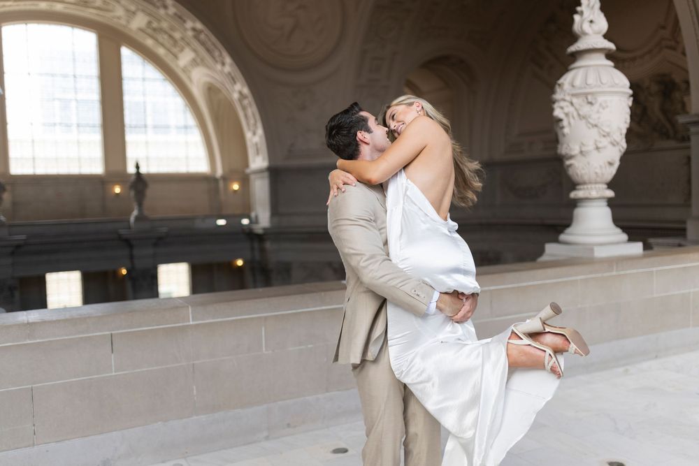 Groom picking up bride and kissing at San Francisco City Hall on the 4th floor