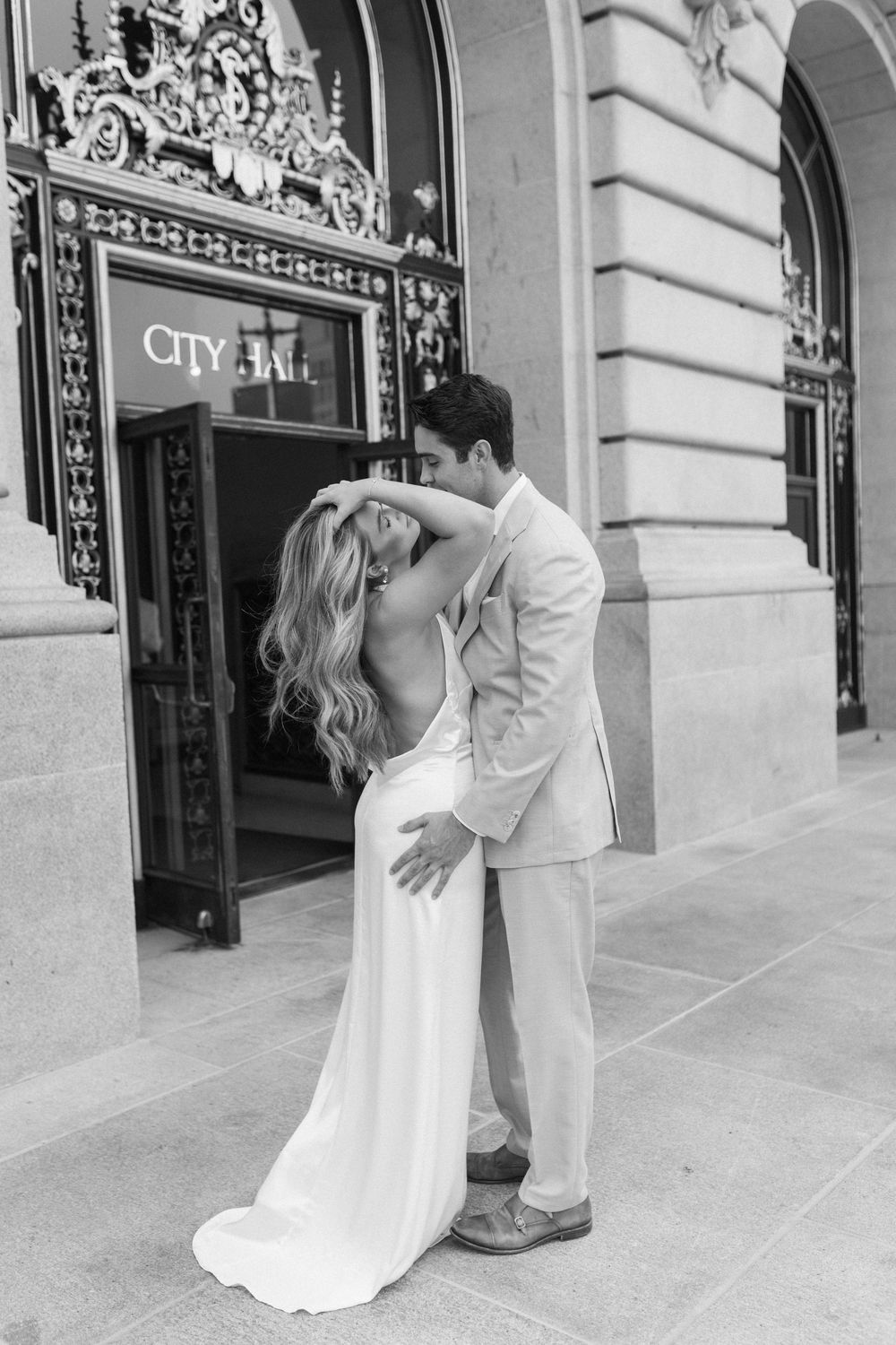 Bride and groom embracing outside of City Hall's front doors