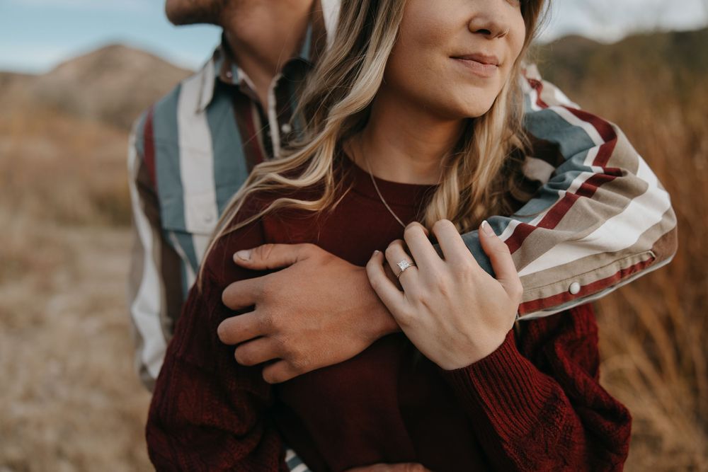 Close up view of someone wearing a burgundy knit sweater embracing outdoors in warm natural lighting.