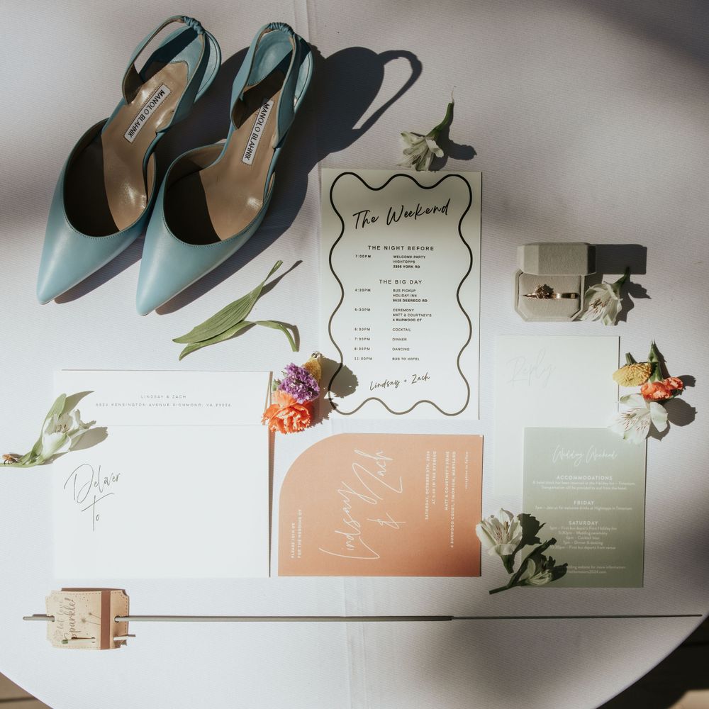 Wedding details flat lay with mint green shoes, floral invitations and golden decor elements.
