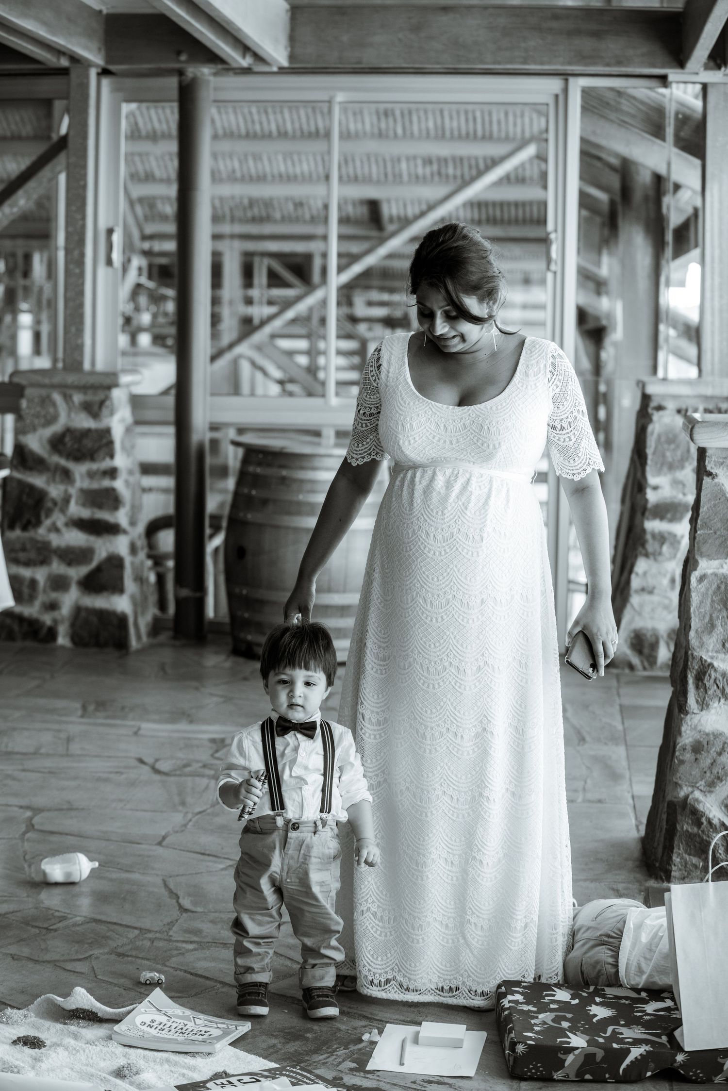 A sweet moment between a parent and toddler in formal attire on a covered porch.