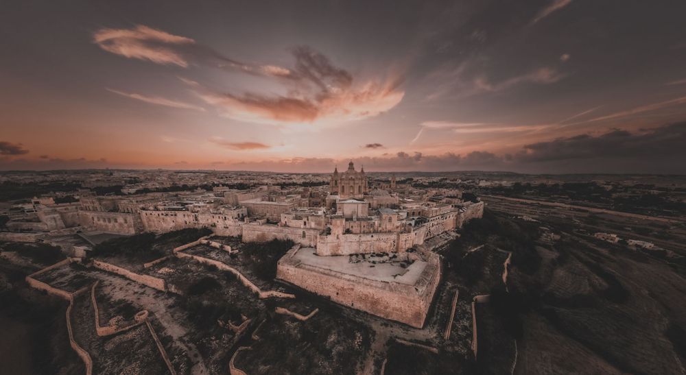 Dramatic sunset panorama over Malta's rocky coastal landscape.