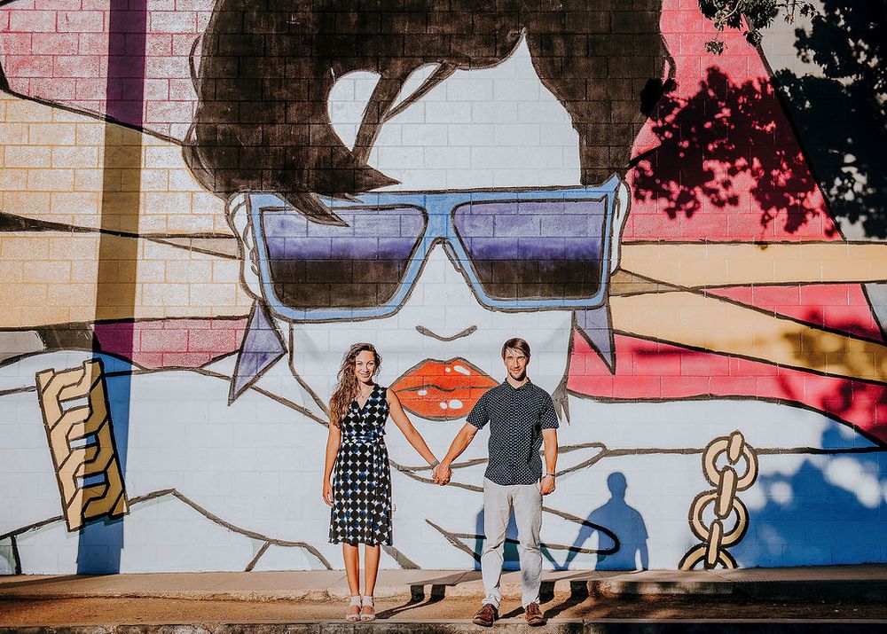 couple during an engagement shoot in front of a mural in santa barbara's funk zone