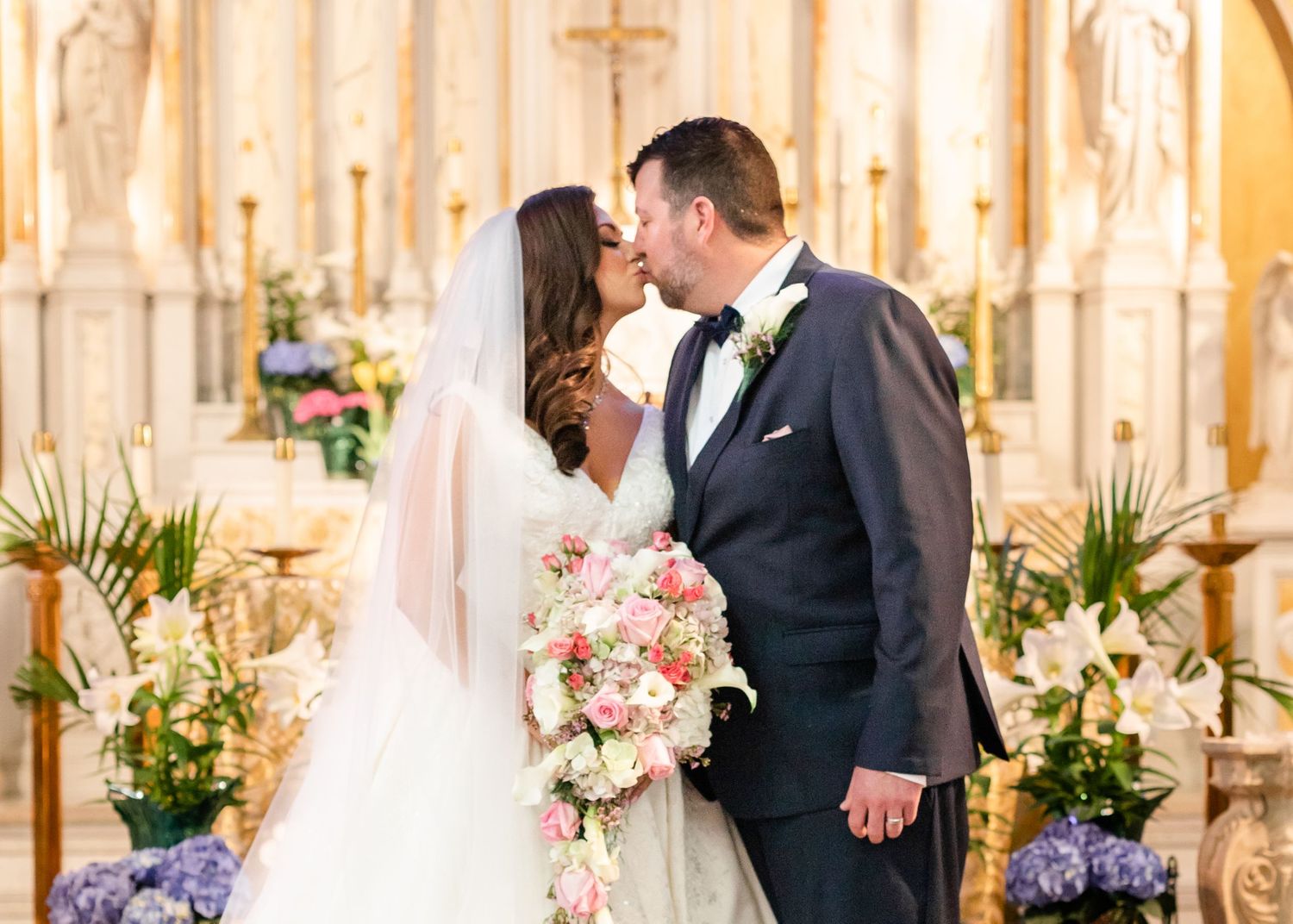 A traditional church wedding ceremony in progress with decorative floral arrangements and golden lighting.