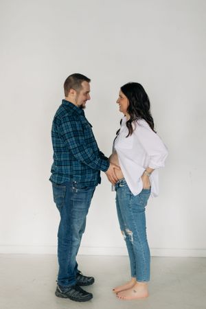 Couple in casual denim and plaid sharing an intimate moment against a white studio backdrop.