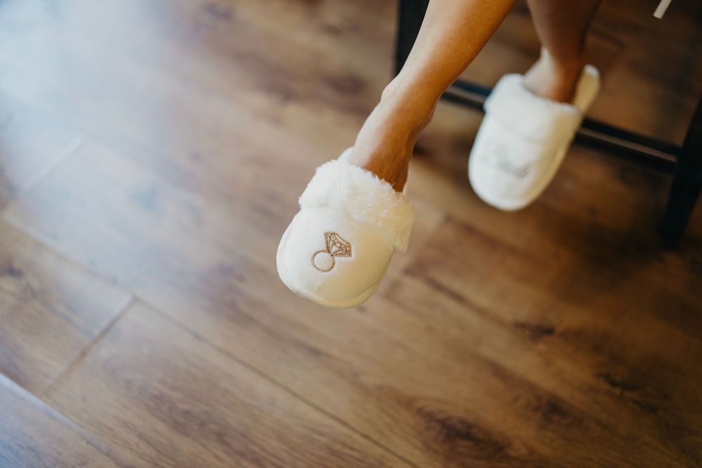 Close-up of wedding shoes on wooden floor during preparation.