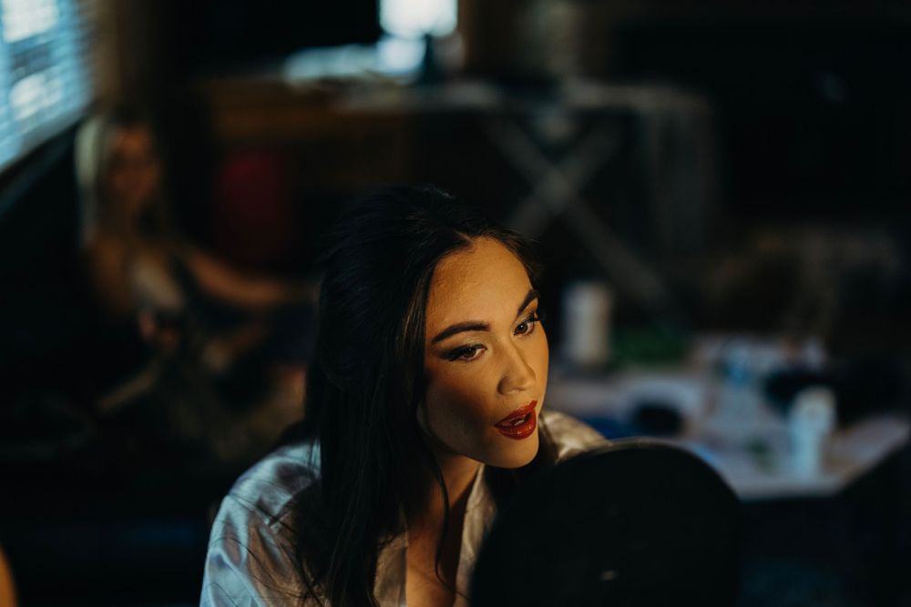 Wedding preparation scene with dramatic lighting and makeup application.