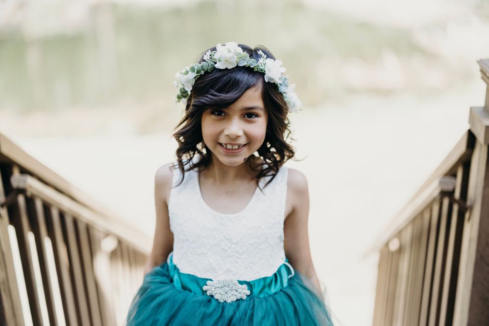 Children in formal attire walking down wooden stairs at outdoor wedding venue.