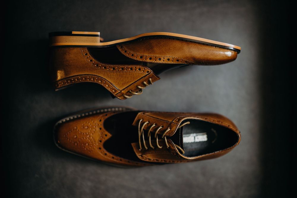 Stylish brown leather dress shoes arranged artistically against dark background.