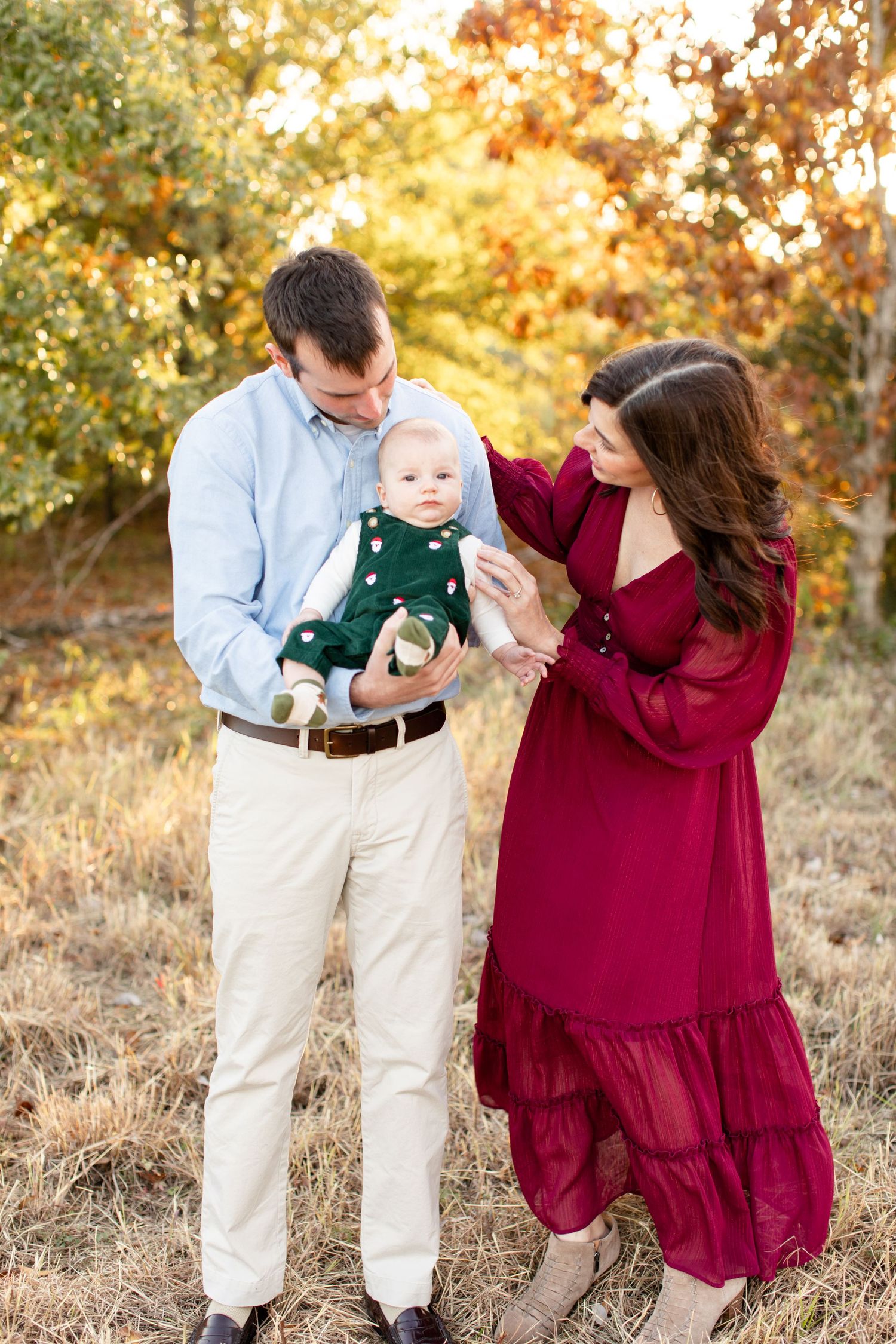 Candid family moment outdoors with burgundy dress and light blue shirt in fall scenery.