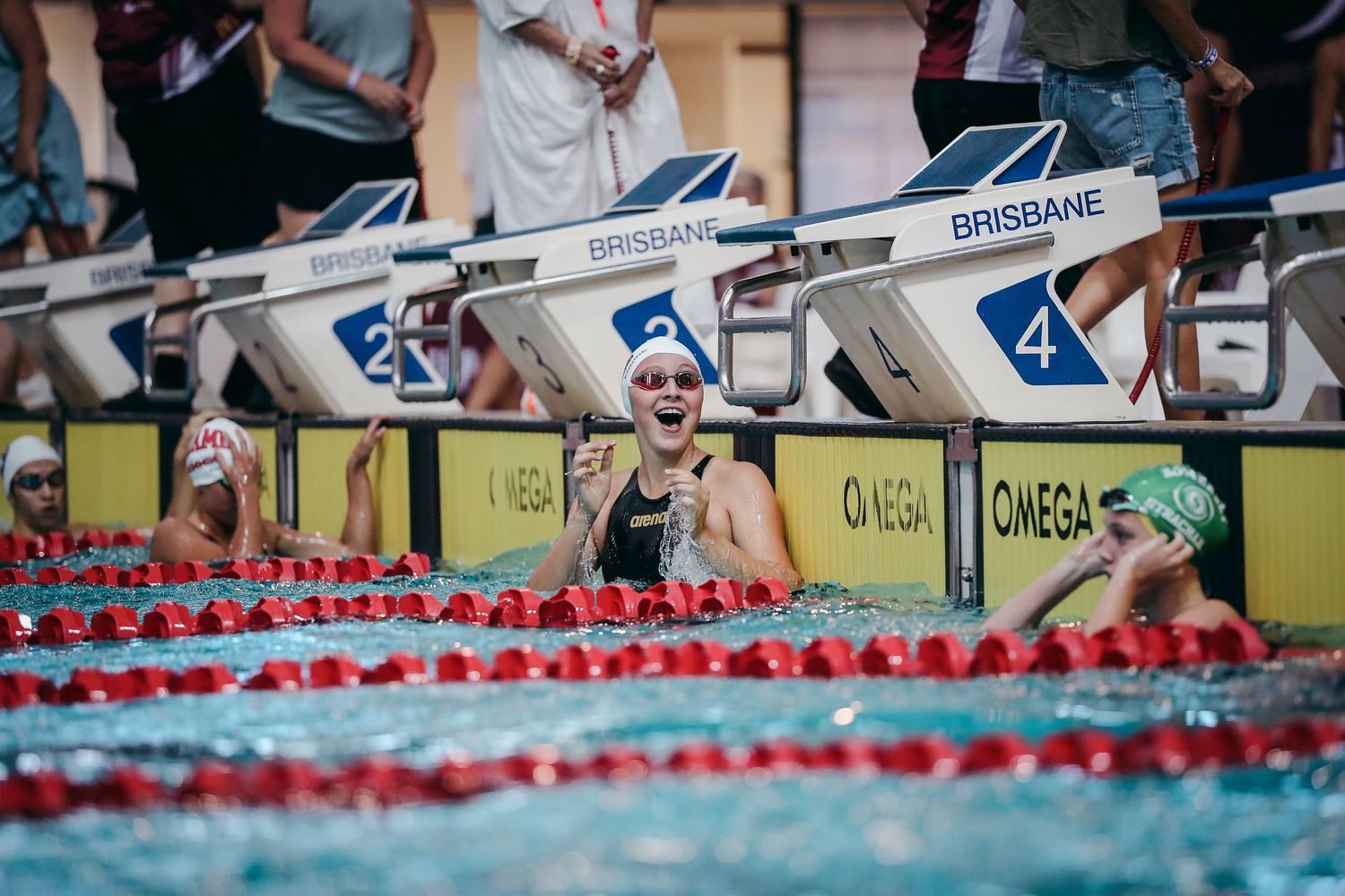Swimmers celebrating at pool edge during competitive swimming event.