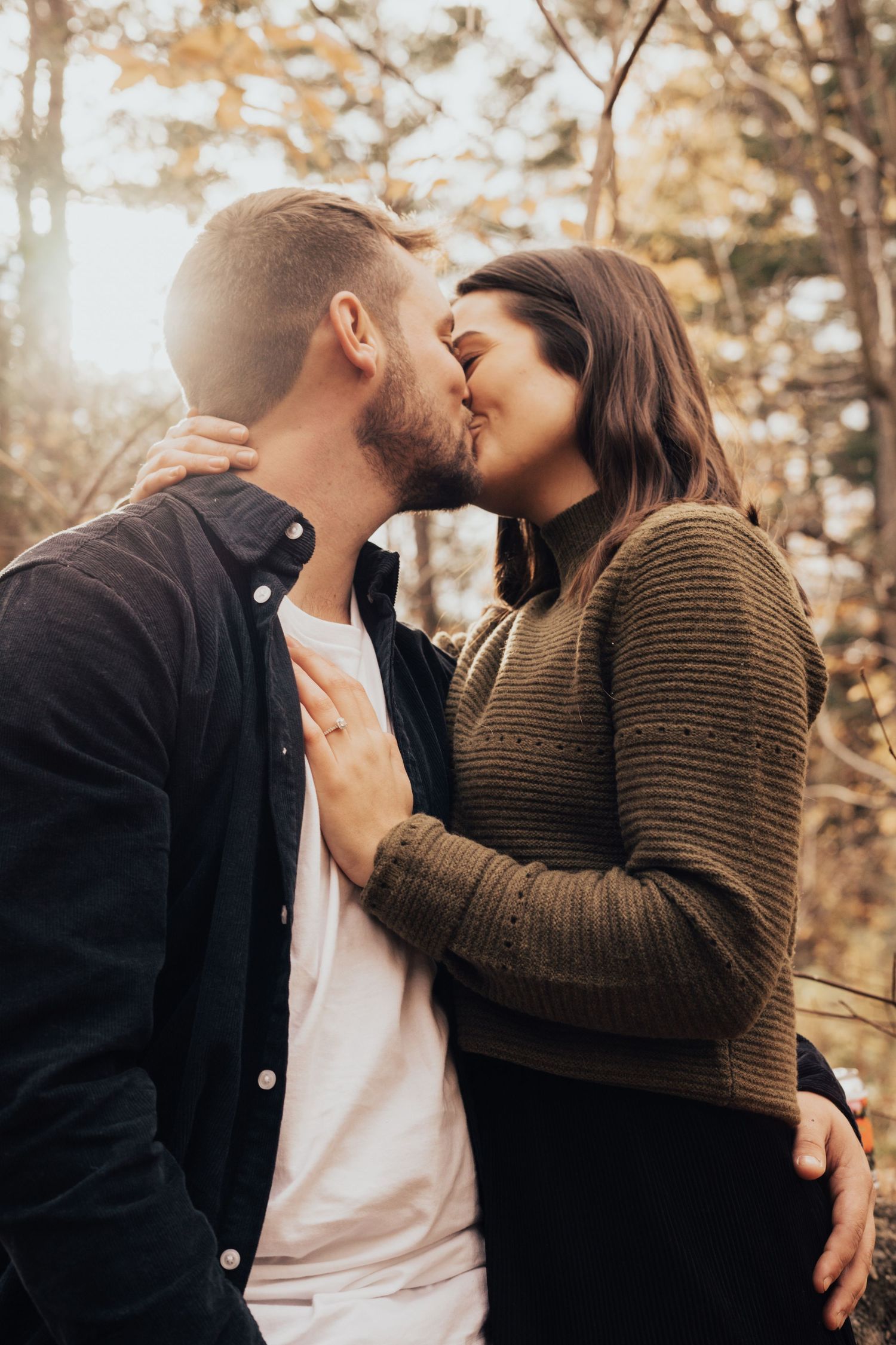 Image of woman and man kissing in forest.