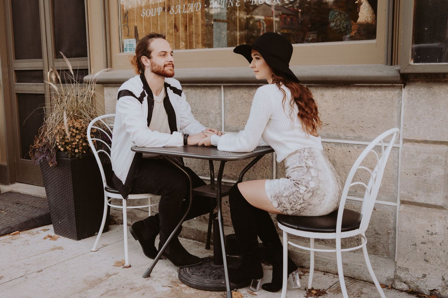 Image of woman and man sitting at a bistro table outside a cafe.