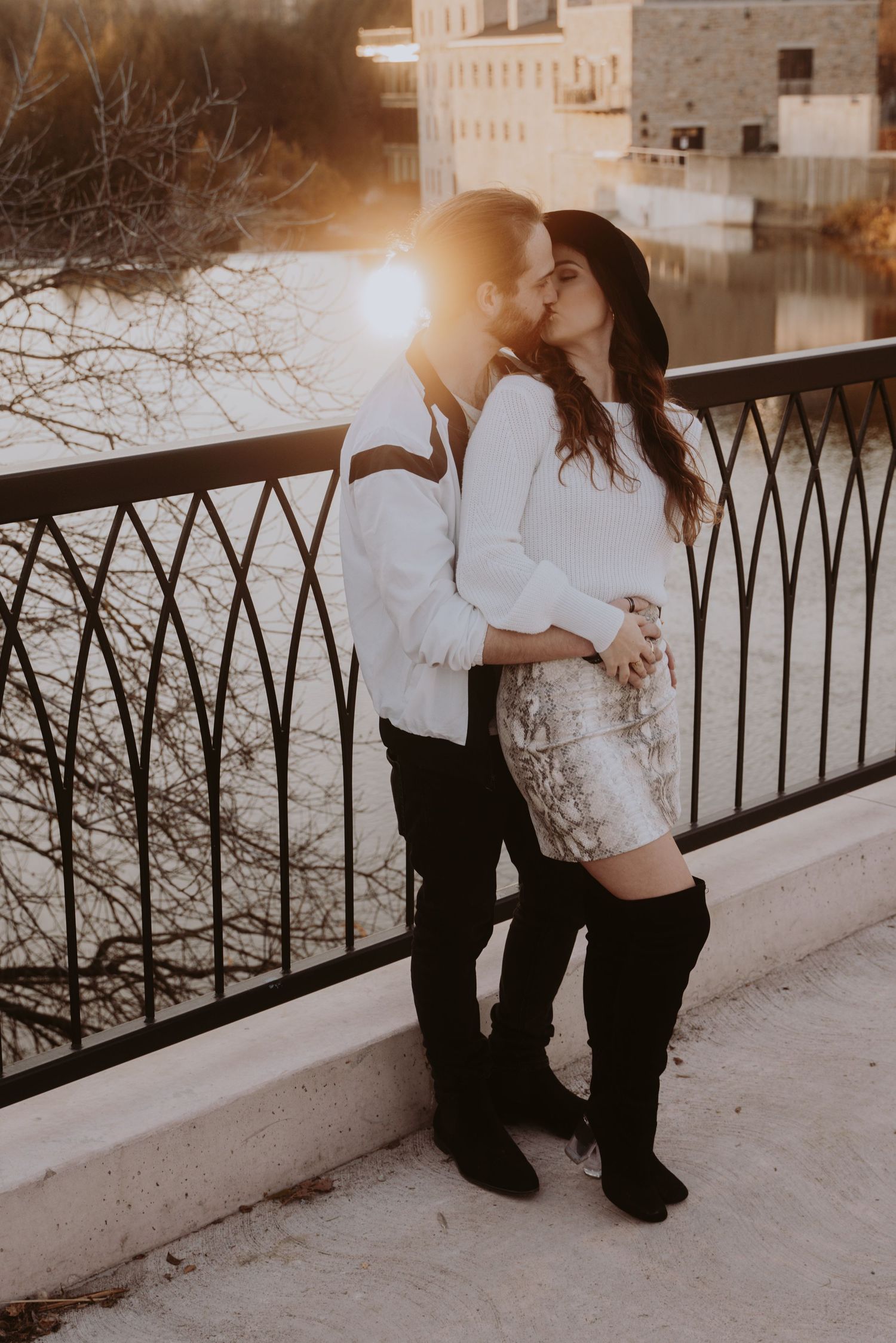 Image of a woman and man kissing on a bridge.