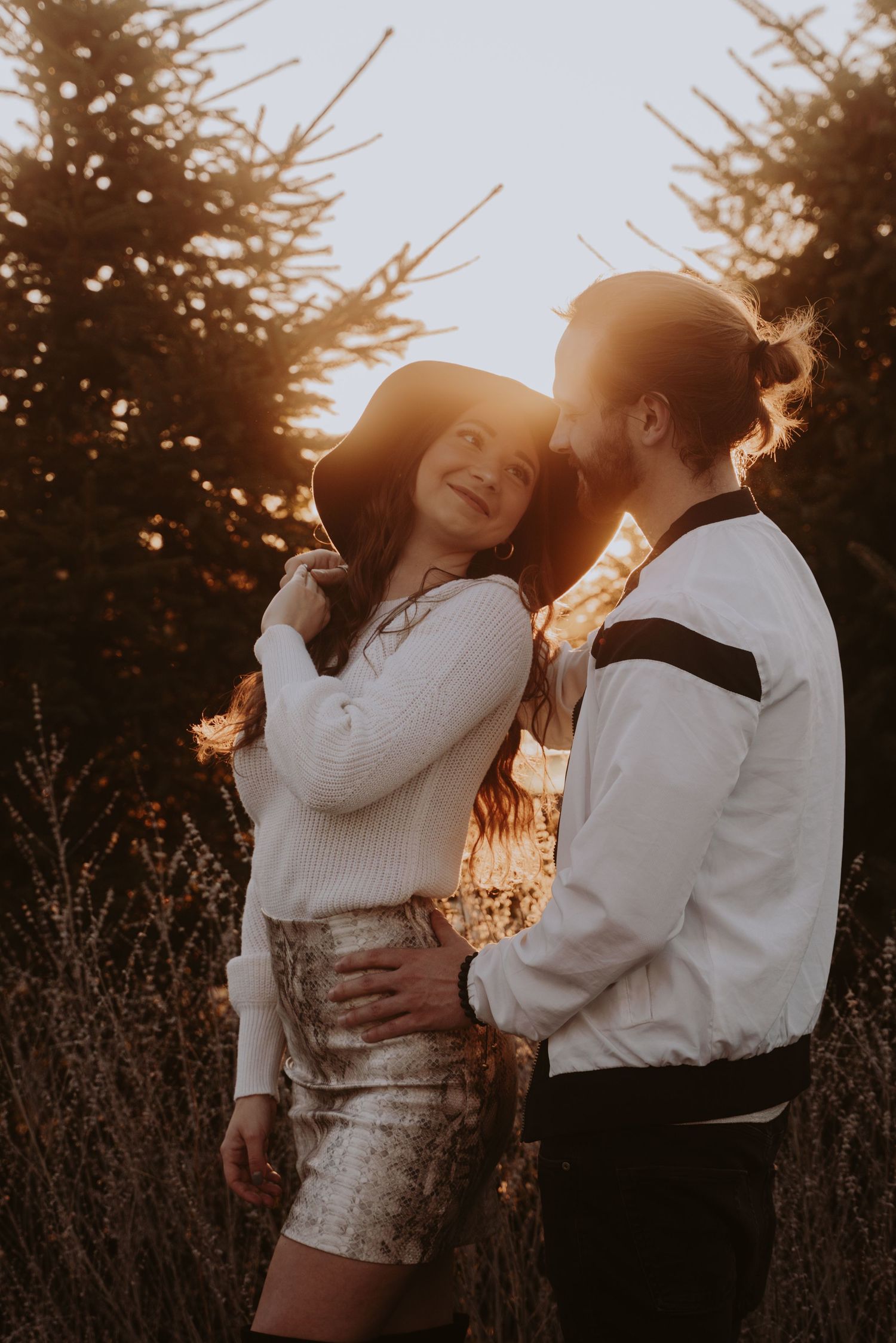 Image of a woman and man smiling at eachother with sunset glow.