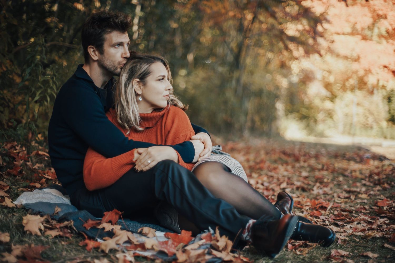 Image of woman and man laying in leaves together.
